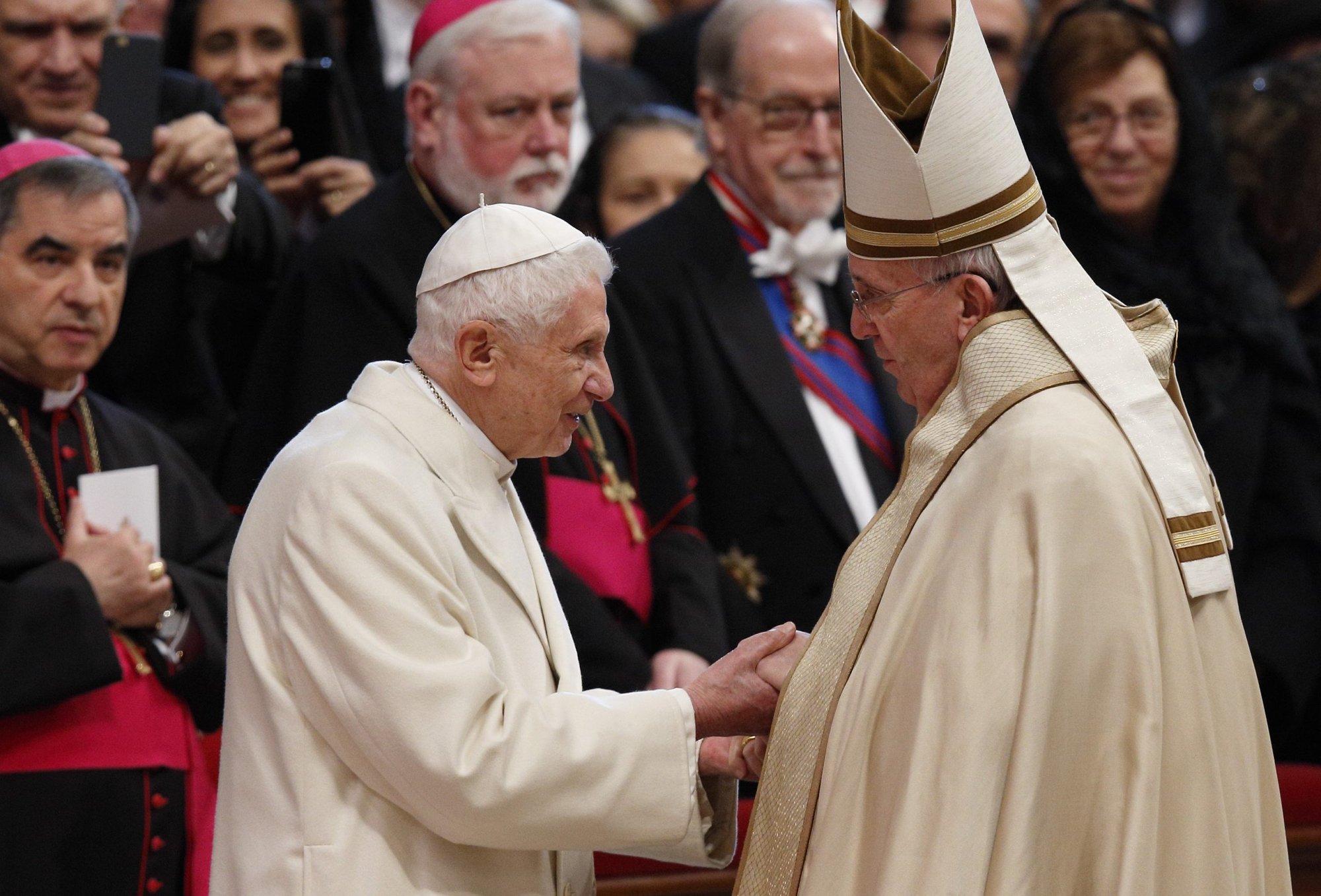 El papa emérito Benedicto XVI y el papa Francisco intercambian saludos al término de un consistorio en el que el papa Francisco creó 20 nuevos cardenales en la basílica de San Pedro del Vaticano el 14 de febrero de 2015. El Papa Benedicto falleció a los 95 años en su residencia del Vaticano. (CNS /Paul Haring)