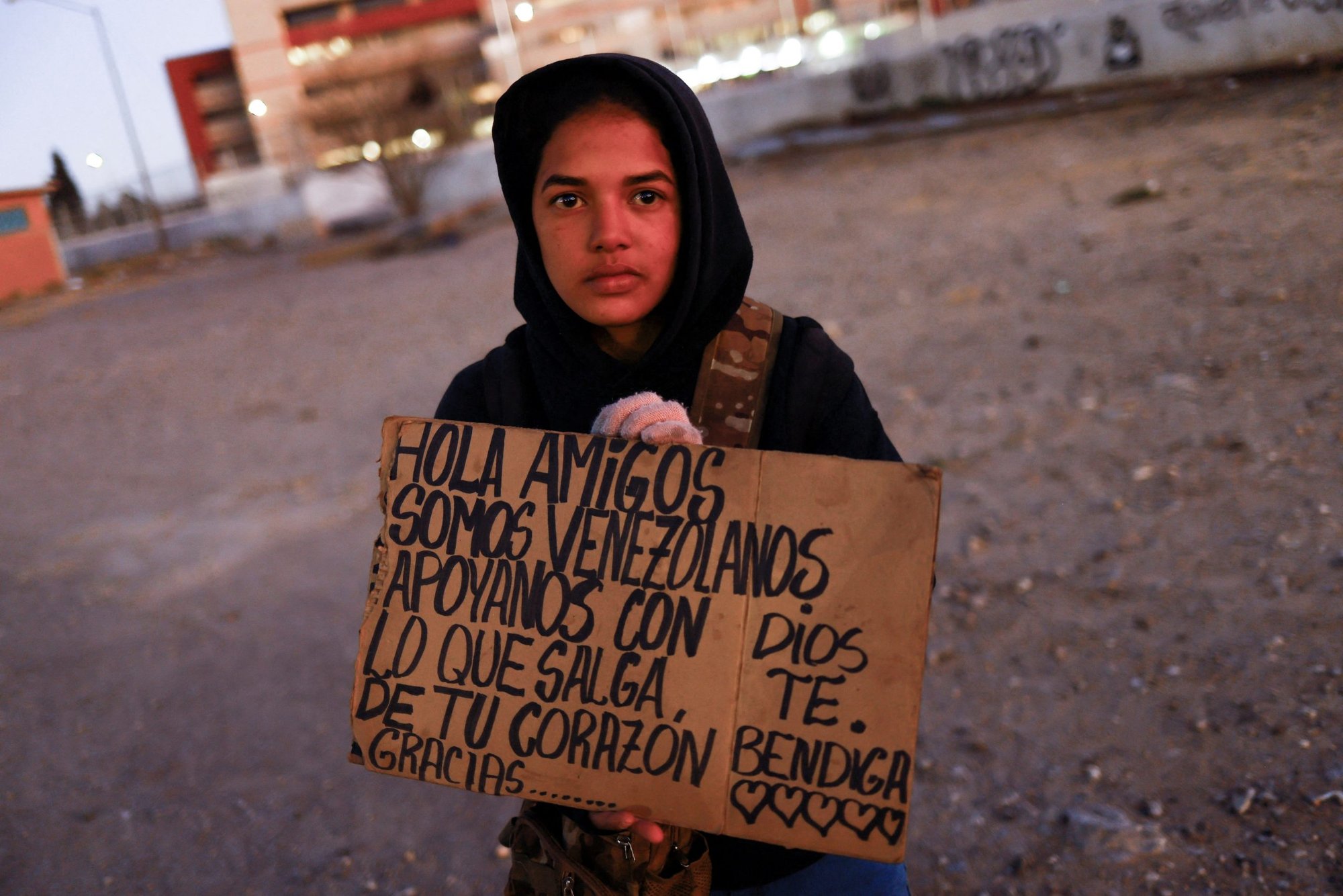 Yalimar Chirinos, una migrante venezolana de 19 años, muestra un cartel cerca de la frontera entre Estados Unidos y México en Ciudad Juárez, México, 7 de enero de 2023. El cartel dice "Hola amigos, somos de Venezuela, apóyennos con lo que les salga del corazón". (Foto OSV News/Jose Luis Gonzalez, Reuters)