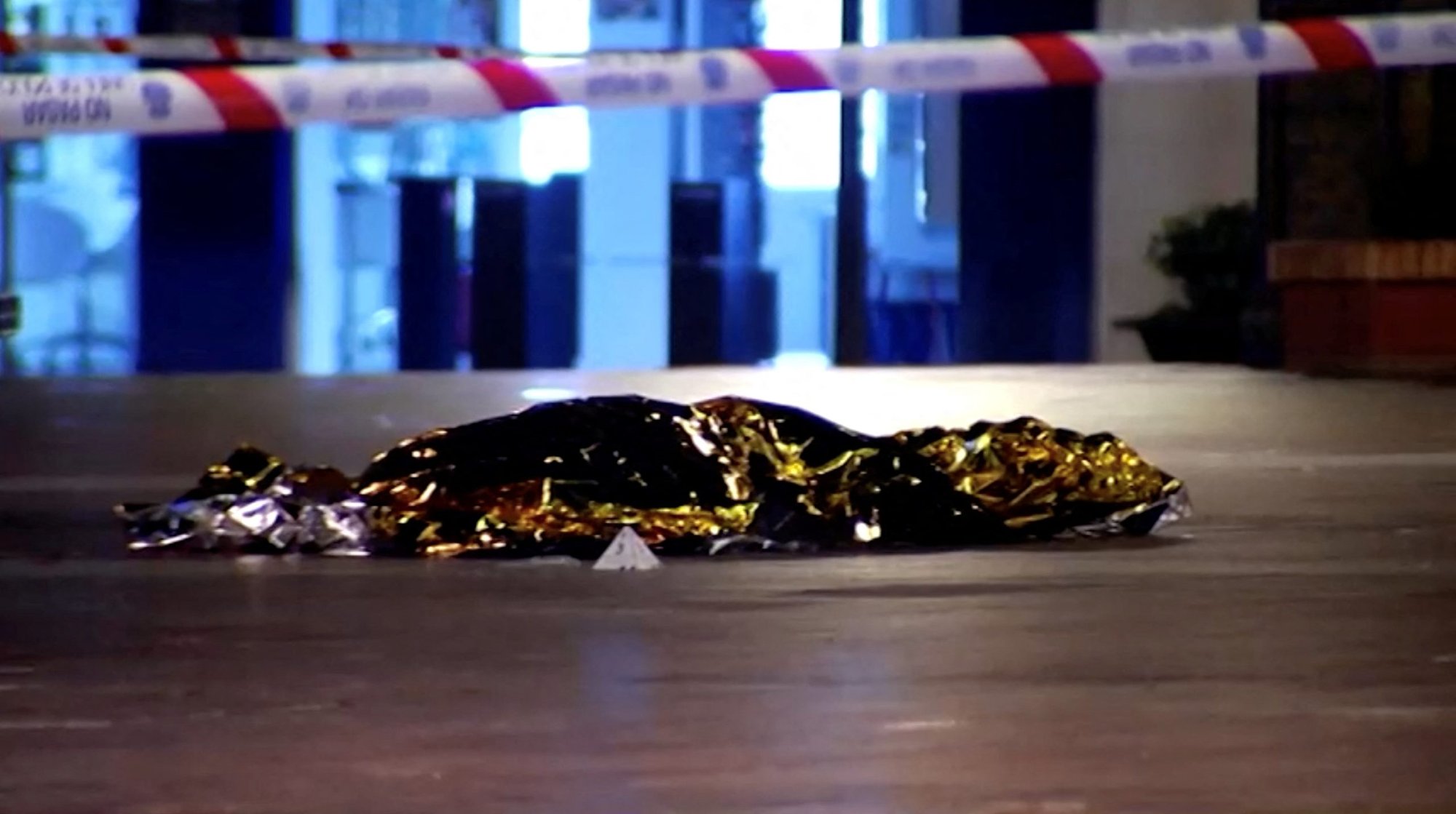 Un cuerpo cubierto con una manta térmica es visto en el lugar de un incidente de apuñalamiento fuera de la Iglesia de Santa María Auxiliadora en Algeciras, España, 25 de enero 2023, en esta captura de pantalla de un video. Según la agencia española de noticias EFE, el atacante, identificado como Yasin Kanza, entró en la iglesia por primera vez en la tarde del 25 de enero y atacó con un machete al padre salesiano Antonio Rodríguez, de 74 años, mientras celebraba la misa. El sacerdote sobrevivió al ataque. A continuación, Kanza se dirigió a la iglesia de Nuestra Señora de La Palma, donde atacó a Diego Valencia, sacristán de la parroquia. Aunque la víctima huyó, Kanza le persiguió e hirió mortalmente a Valencia. Su cuerpo fue encontrado en la Plaza Alta, frente a la iglesia. (Foto OSV News/FORTA vía Reuters)