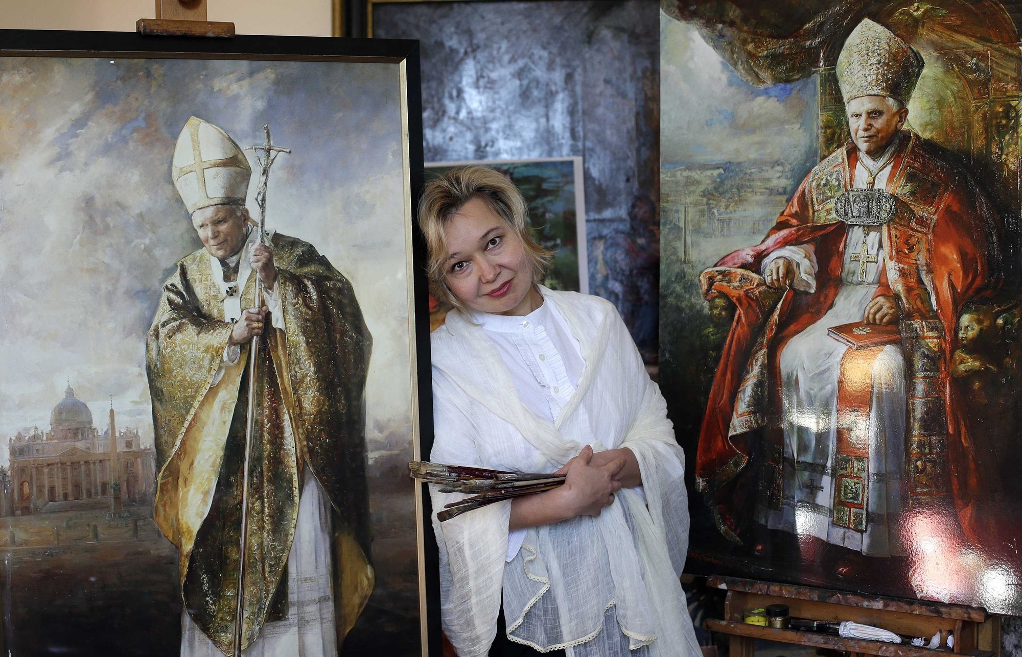 La pintora rusa Natalia Tsarkova posa junto a las copias de los retratos que pintó de Benedicto XVI y Juan Pablo II en su estudio del centro de Roma en 2013. (CNS/Max Rossi, Reuters)