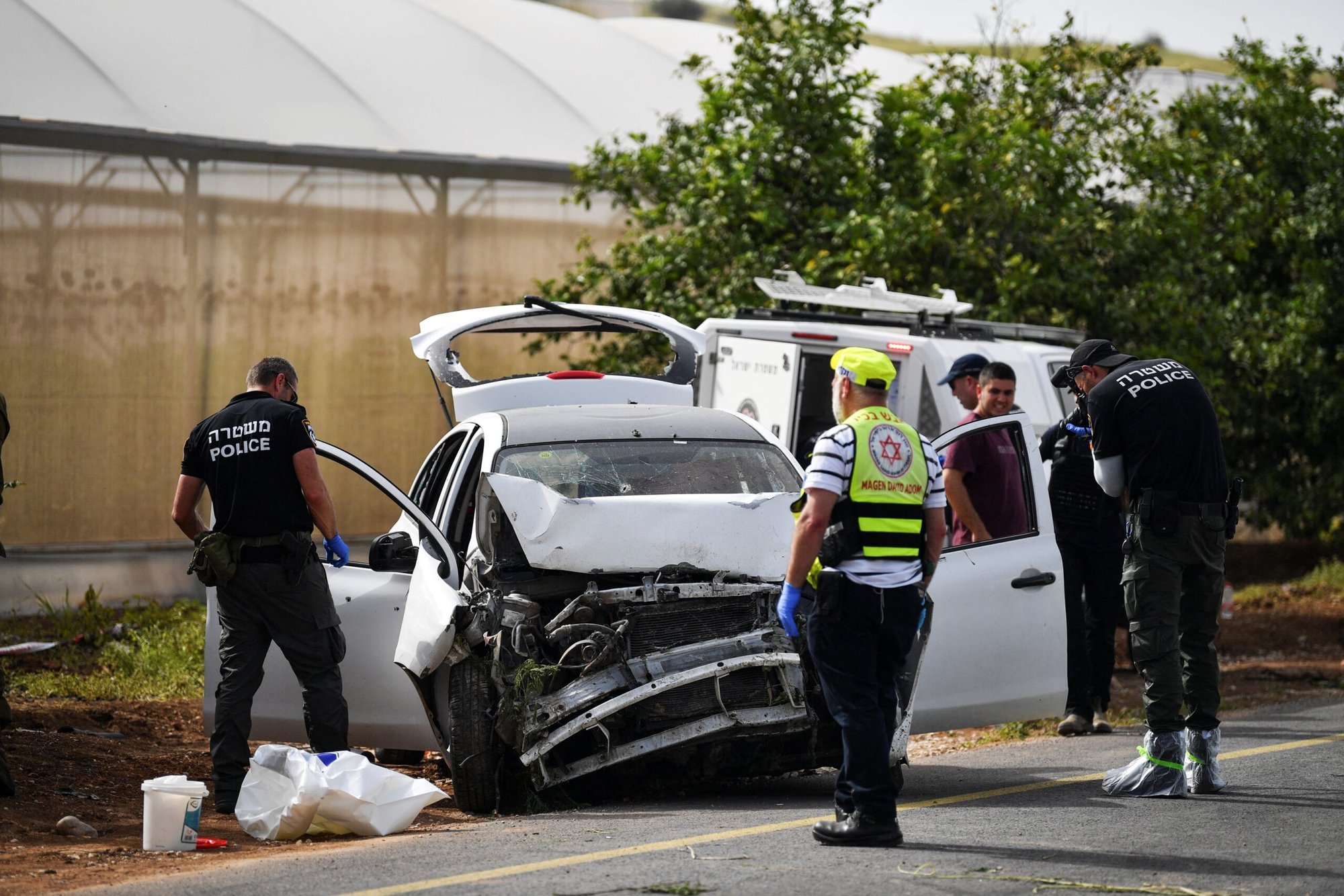 Médicos y policías israelíes revisan un coche dañado en el lugar de un tiroteo, en el valle del Jordán, en Cisjordania ocupada por Israel, el 7 de abril de 2023. Una madre británico-israelí y sus dos hijas murieron en un atentado terrorista con coche bomba. (OSV News photo/Gil Eliyahu, Reuters)