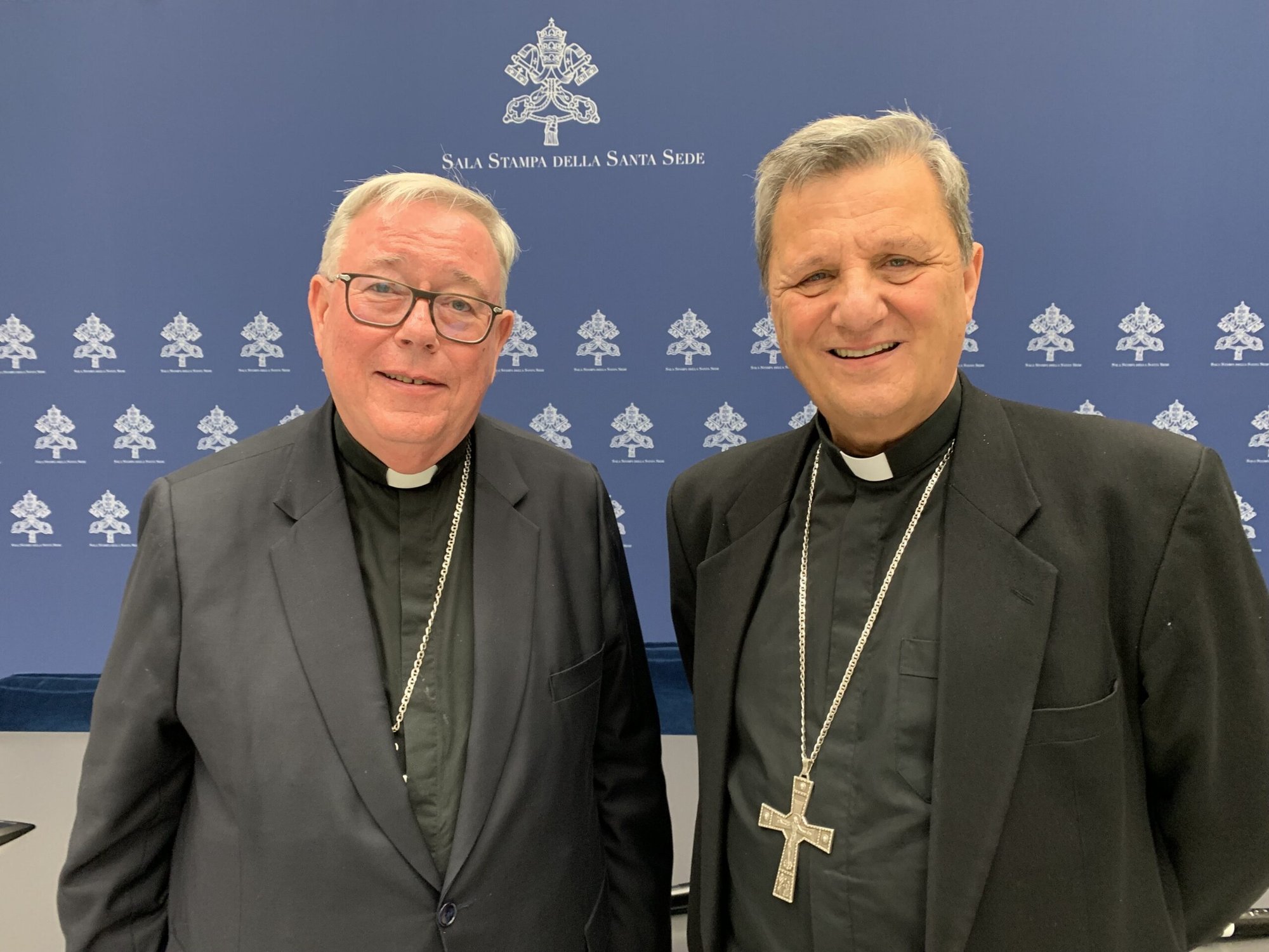 El cardenal Jean-Claude Hollerich, relator general del Sínodo de los Obispos, y el cardenal Mario Grech, secretario general del sínodo, posan para una foto en la oficina de prensa del Vaticano el 26 de abril de 2023, después de hablar con los periodistas sobre la decisión del Papa Francisco de que las mujeres y los laicos sean miembros con derecho a voto del sínodo. (CNS /Cindy Wooden)
