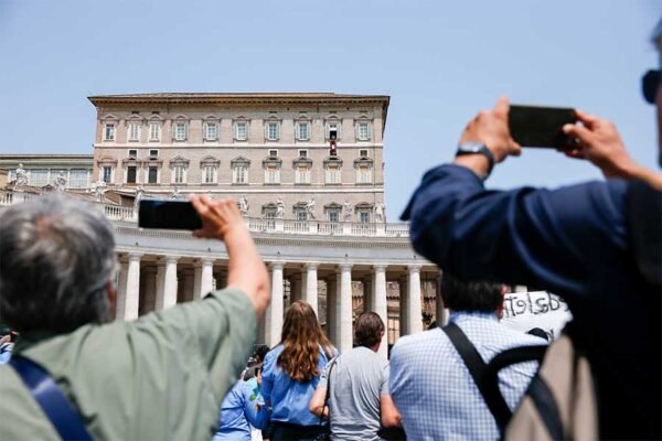 Visitantes apuntan las cámaras de sus teléfonos móviles al Papa Francisco mientras reza el Ángelus desde la ventana de su estudio con vistas a la Plaza de San Pedro en el Vaticano el 18 de junio de 2023. (CNS/Lola Gomez)