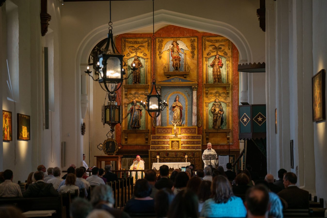 El párroco de la Misión San Gabriel, el padre John Molyneux, habla al comienzo de la ceremonia de bendición del interior restaurado de la histórica iglesia, el 27 de junio. (John Rueda)