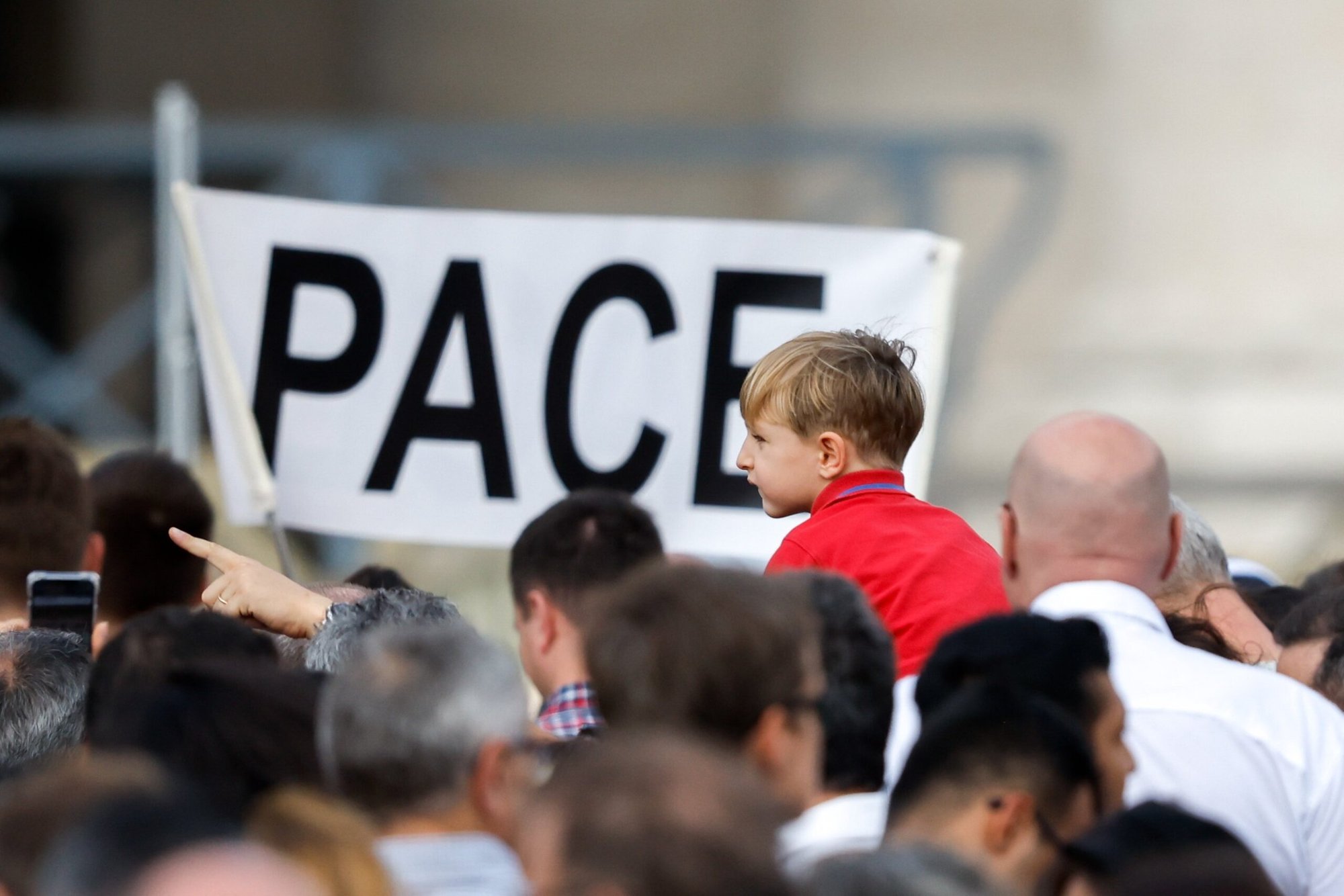 Un niño está cerca de un cartel que dice "Pace", paz en italiano, mientras los visitantes se reúnen para rezar el Ángelus con el Papa Francisco en la Plaza de San Pedro en el Vaticano el 29 de octubre de 2023. (Foto CNS/Lola Gomez)