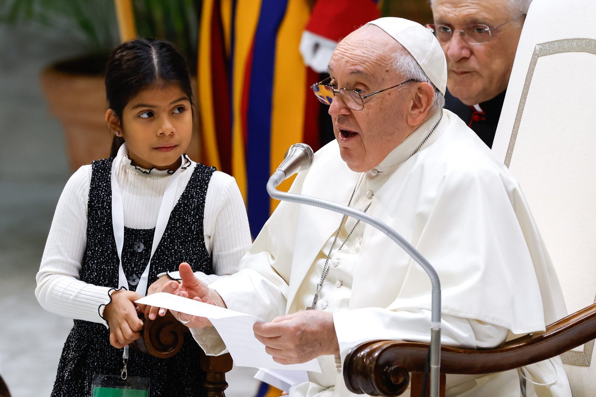 Una niña escucha al Papa Francisco responder a las preguntas de niños de diferentes partes del mundo durante el acto "Aprendamos de los niños y las niñas" en el Aula Pablo VI del Vaticano el 6 de noviembre de 2023. (Foto CNS/Lola Gomez)