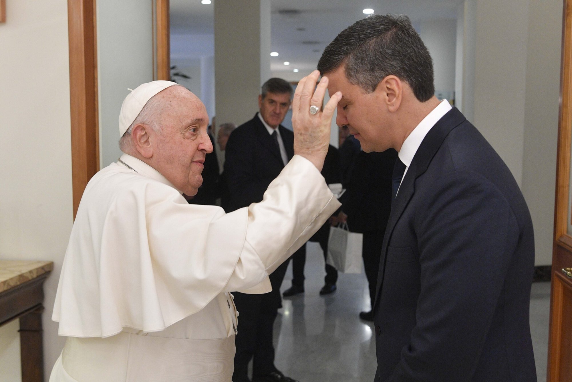 El Papa Francisco, que se recupera de una inflamación pulmonar, bendice al presidente de Paraguay, Santiago Peña Palacios, al término de su encuentro en la Domus Sanctae Marthae del Vaticano el 27 de noviembre de 2023. La foto indica que la cánula que el Papa tenía en su mano derecha el día anterior para antibióticos intravenosos había sido retirada. (Foto CNS/Vatican Media)