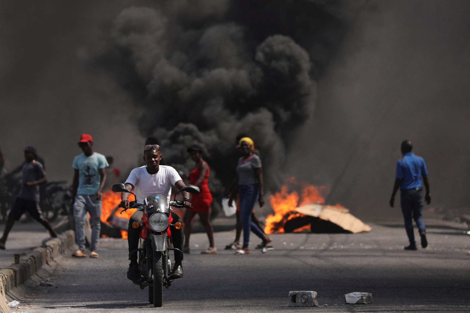 Un hombre pasa en coche junto a una barricada en llamas durante una protesta contra el gobierno del primer ministro haitiano Ariel Henry y la inseguridad en Puerto Príncipe el 1 de marzo de 2024. (Foto de OSV News/Ralph Tedy Erol, Reuters)