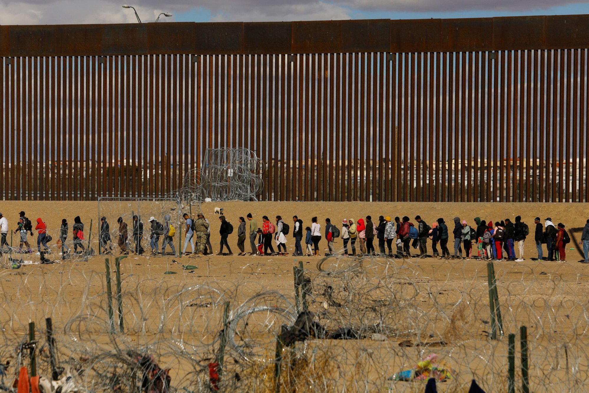 Migrantes que buscan asilo en Estados Unidos se reúnen cerca del muro fronterizo el 22 de enero de 2024, visto desde Ciudad Juárez, México, después de cruzar una valla de alambre de púas y mientras miembros de la Guardia Nacional de Texas hacen guardia. (OSV News /Jose Luis Gonzalez, Reuters)