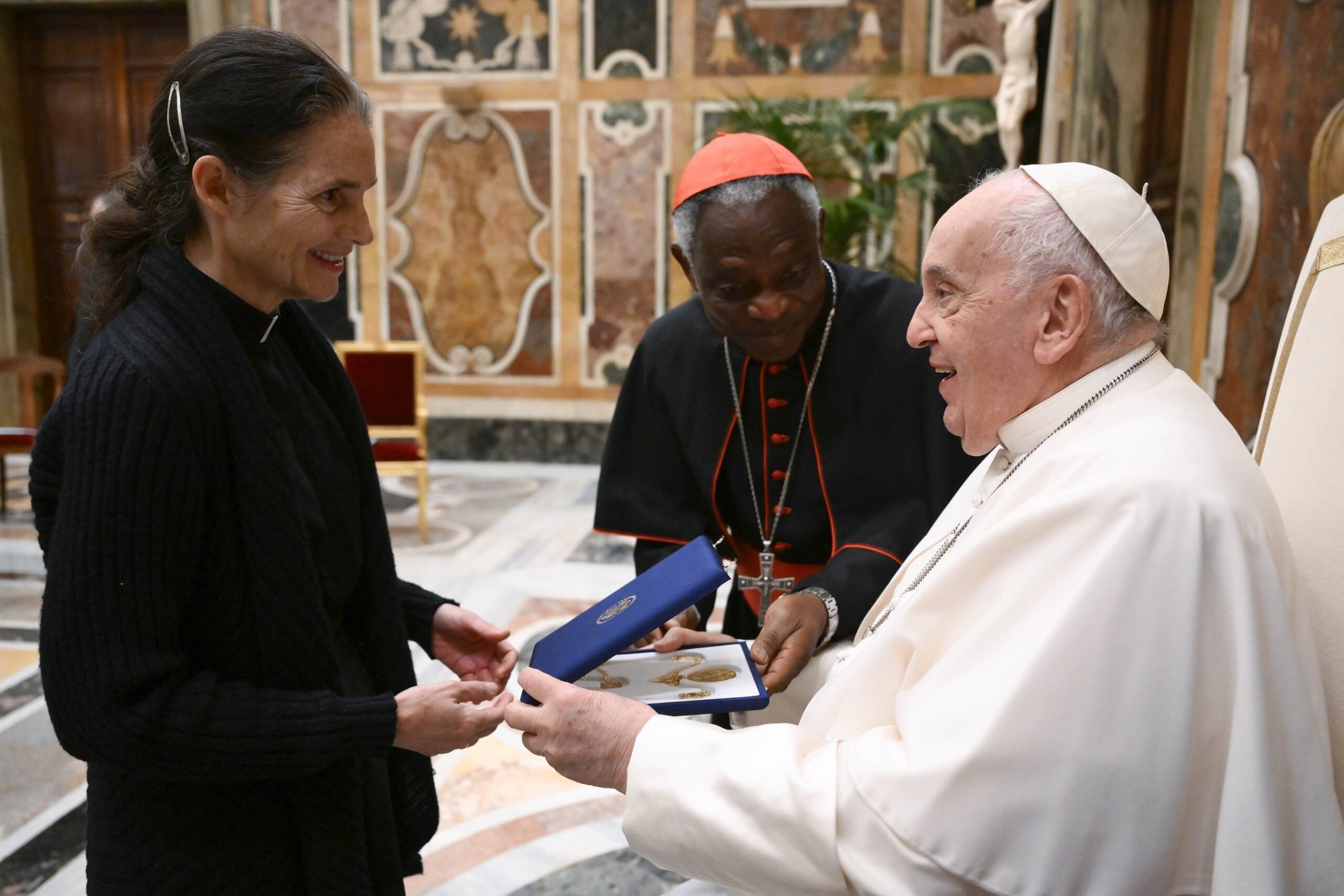 La reverenda Sabina Alkire, académica de la Pontificia Academia de Ciencias Sociales, entrega un regalo al Papa Francisco durante una reunión para la sesión plenaria de la academia en el Vaticano el 11 de abril de 2024. El cardenal Peter Turkson, canciller de la academia, aparece en el centro. (Foto CNS/Vatican Media)