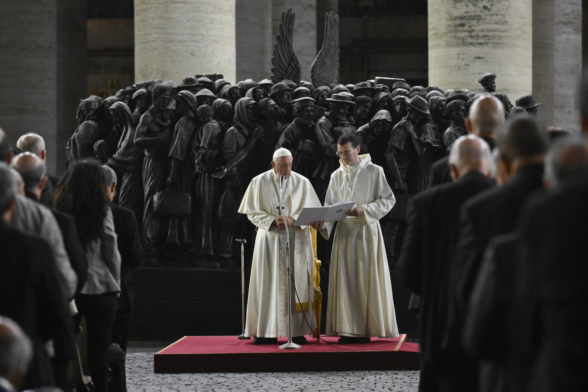 El Papa Francisco dirige a los miembros de la asamblea del Sínodo de los Obispos en la oración por los migrantes y refugiados frente a la estatua «Ángeles desprevenidos», en la Plaza de San Pedro el 19 de octubre de 2023. La escultura, obra del canadiense Timothy Schmalz, representa una barca con 140 figuras de migrantes de diversas épocas históricas y varias naciones. (CNS /Vatican Media)