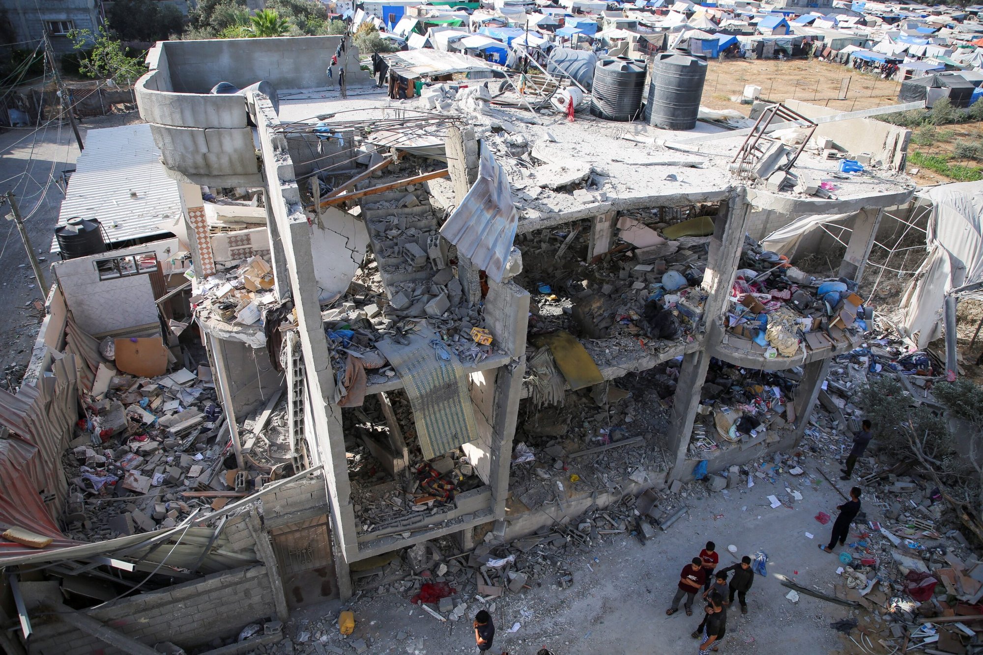 Un grupo de personas junto a una casa destruida en Rafah, en el sur de la Franja de Gaza, el 3 de mayo de 2024, tras un ataque aéreo israelí en medio del actual conflicto entre Israel y el grupo islamista palestino Hamás. (Foto de OSV News/Hatem Khaled, Reuters)