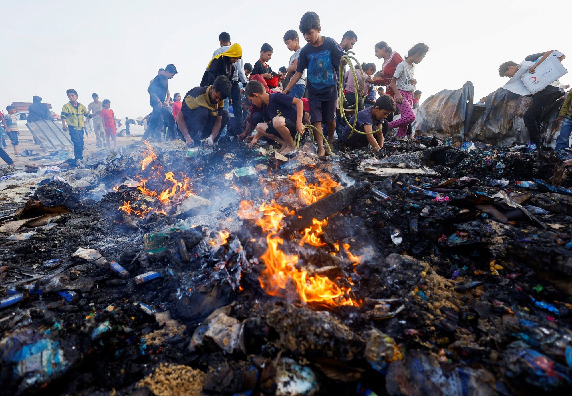 Palestinos buscan comida entre escombros en llamas el 27 de mayo de 2024, tras un ataque aéreo israelí contra una zona designada para desplazados en Rafah, en el sur de la Franja de Gaza. (Foto de OSV News/Mohammed Salem, Reuters)