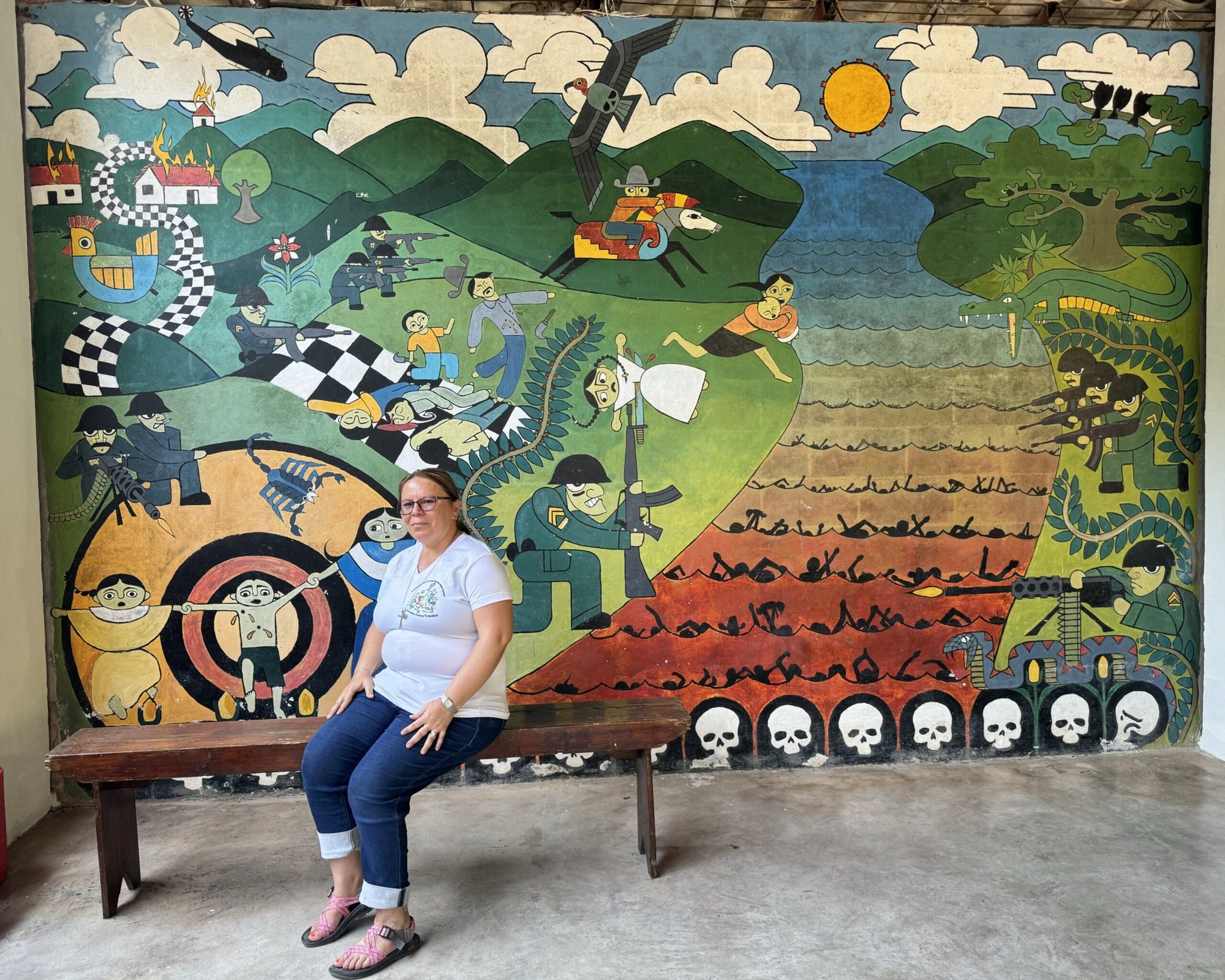 La hermana de la Providencia Vilma Franco se sienta en un banco en su ciudad natal de Arcatao, El Salvador, el 27 de abril de 2024, frente a un mural que representa la masacre de 1980 en el río Sumpul. Cada año, organizaciones como la Asociación Sumpul recuerdan la masacre de más de 600 personas por las fuerzas armadas salvadoreñas, un esfuerzo para educar y prevenir que tales actos se repitan. (Foto OSV News/Rhina Guidos, GSR)