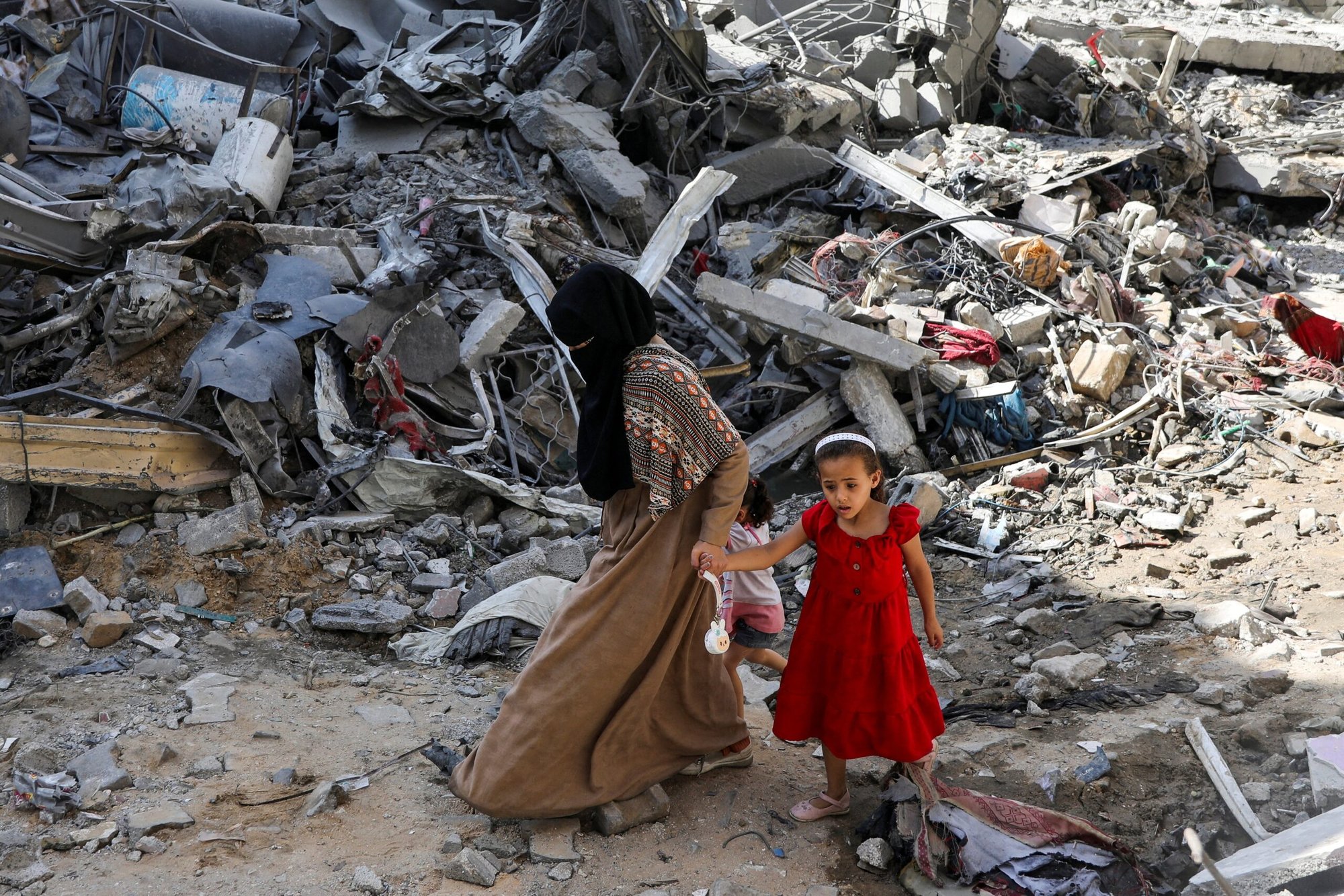 Una mujer y una niña caminan entre los escombros en el campo de refugiados de Nuseirat, en el centro de la Franja de Gaza, el 9 de junio de 2024, tras los ataques israelíes en la zona, donde fueron rescatados rehenes israelíes, en medio del conflicto entre Israel y Hamás. (Foto de OSV News/Abed Khaled, Reuters)