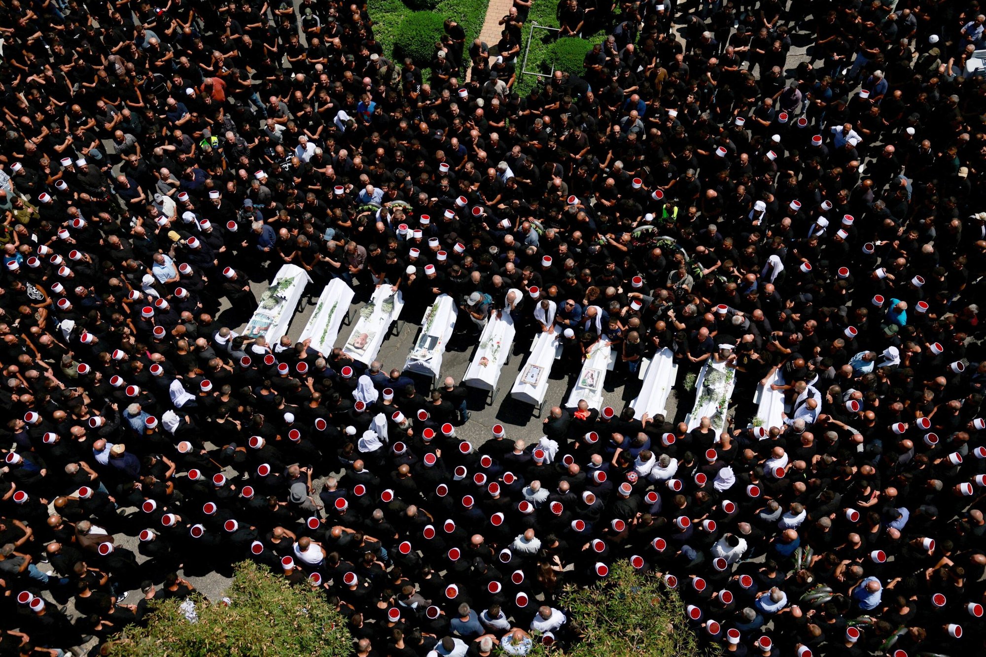 Un grupo de personas se reúne el 28 de julio de 2024 durante el funeral de los niños que murieron en un campo de fútbol por un ataque con misiles en Majdal Shams, un pueblo druso en los Altos del Golán ocupados por Israel. Según las autoridades israelíes, un cohete lanzado desde Líbano alcanzó el campo de fútbol y mató a 12 niños y adolescentes, en lo que el ejército calificó como el ataque más mortífero contra civiles desde el 7 de octubre de 2023. Oriente Próximo se prepara para un posible estallido de violencia tras el ataque. (Foto de OSV News/Ammar Awad, Reuters)