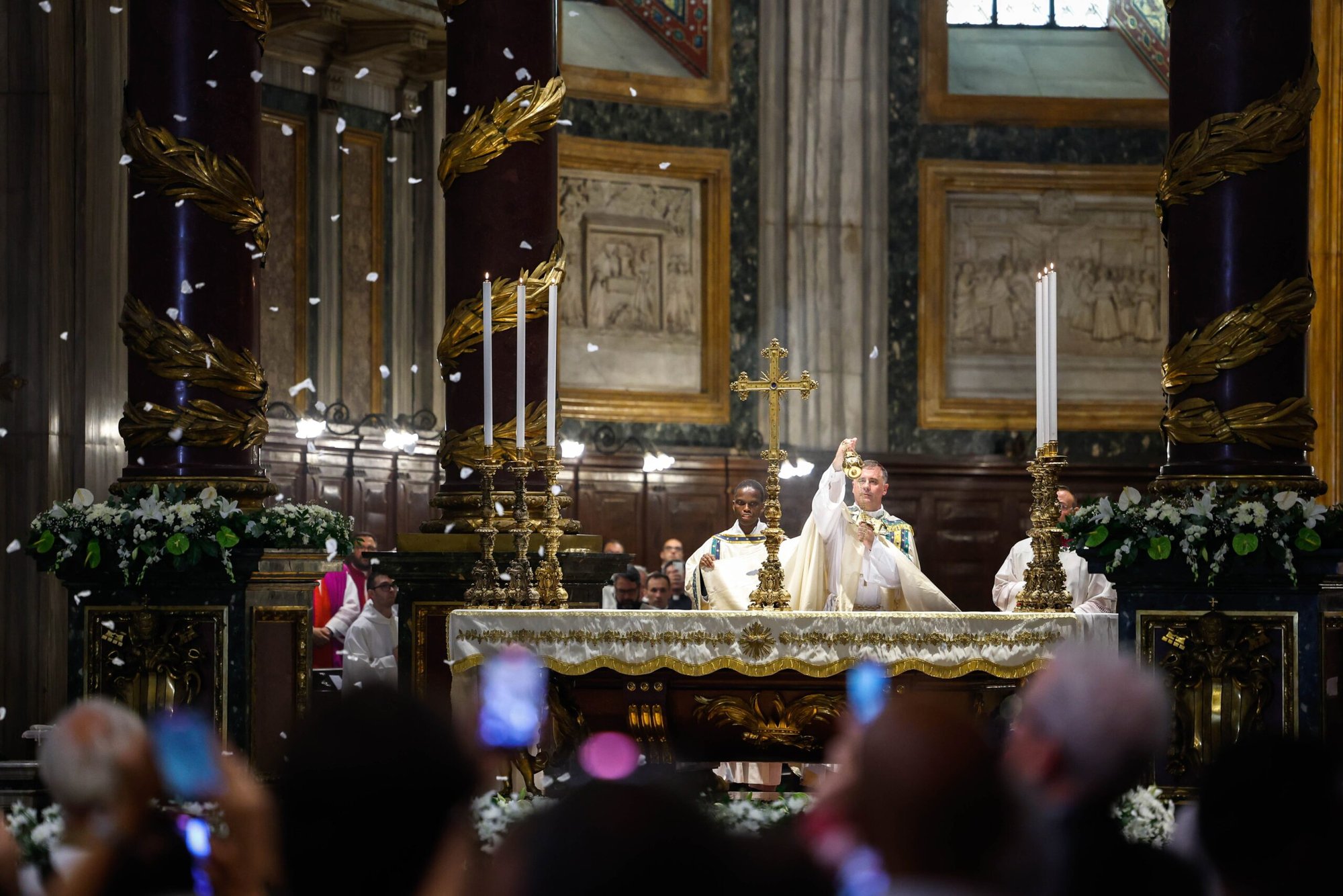 El arzobispo Rolandas Makrickas, arcipreste coadjutor de la Basílica de Santa María la Mayor de Roma, quema incienso mientras caen pétalos de rosa blanca del techo de la basílica el 5 de agosto de 2024, durante la oración vespertina en la fiesta de la dedicación de la basílica. Según la tradición, el 5 de agosto de 358, María hizo caer nieve para marcar el lugar de la colina del Esquilino de Roma donde quería que se construyera una iglesia en su honor. (CNS photo/Lola Gomez)
