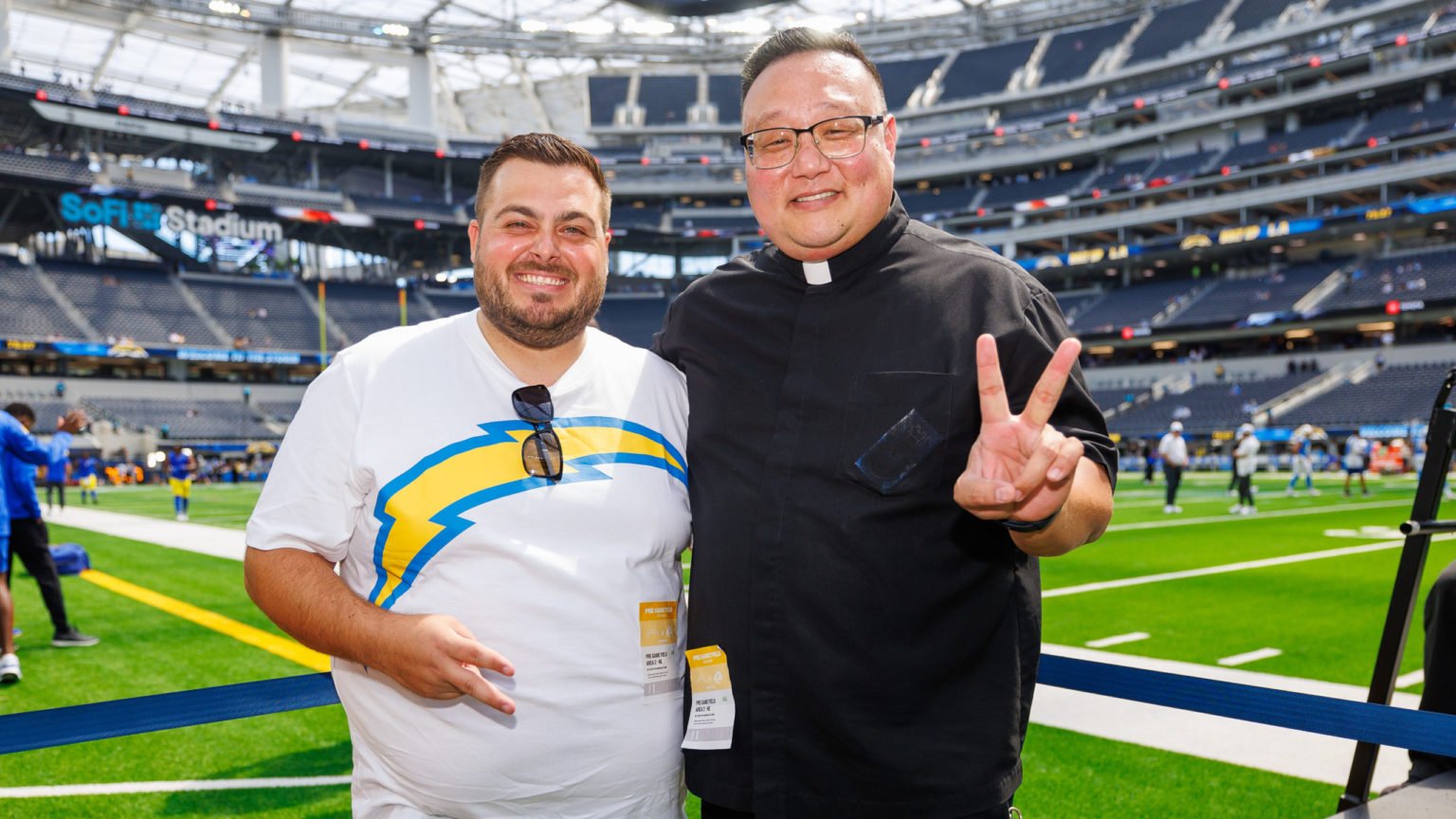 El padre Richard Sunwoo, a la derecha, posa con Niko Rudela, hermano del padre Marko Rudela, durante un partido de pretemporada de los Chargers el 17 de agosto. (Los Angeles Chargers)