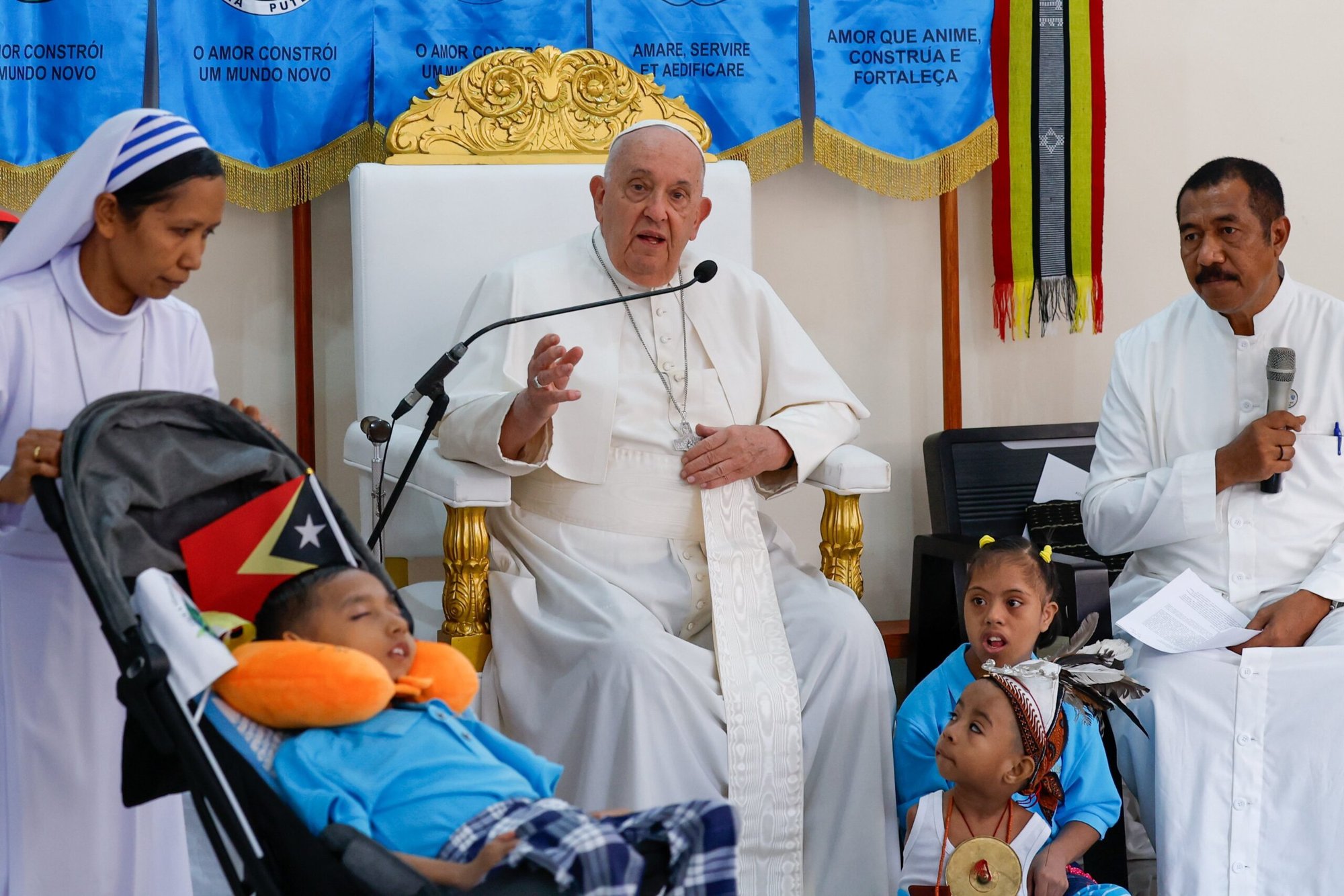 El Papa Francisco habla de la importancia de cuidar de los demás y dejarse cuidar por Dios mientras Silvan, a la izquierda, duerme profundamente en la escuela Irmas Alma de Dili, Timor Oriental, el 10 de septiembre de 2024 (Foto CNS/Lola Gomez)