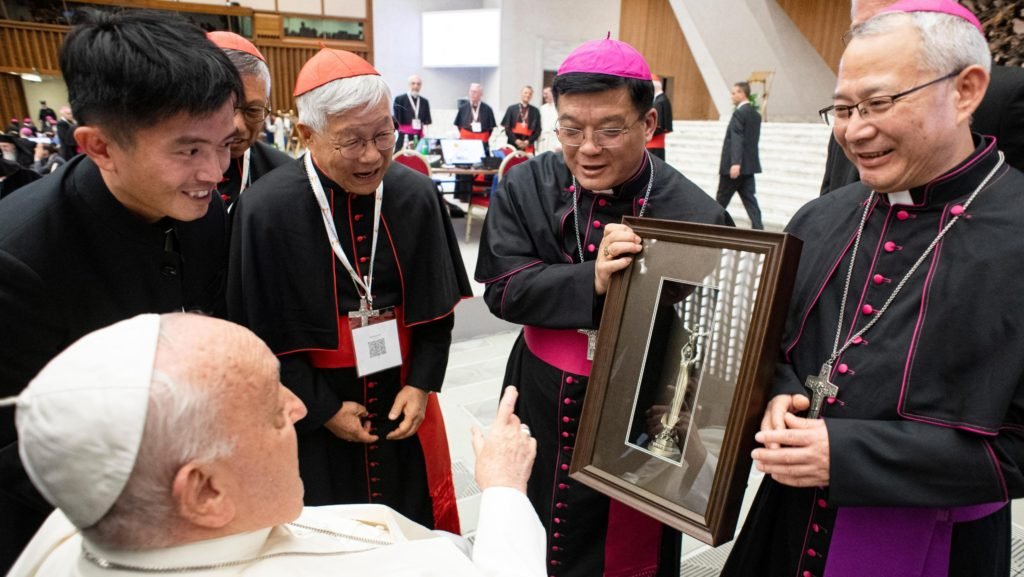 Los obispos Joseph Yang Yongqiang de Hangzhou, en el centro, y Vincent Zhan Silu de Funing-Mindong, a la izquierda, los dos miembros del Sínodo de los Obispos de China continental entregan al Papa Francisco un regalo durante una pausa en la reunión del Sínodo de los Obispos en el Aula de Audiencias Pablo VI en el Vaticano el 2 de octubre de 2024. (CNS photo/Vatican Media)