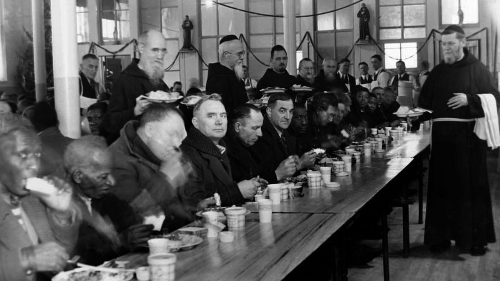 El padre capuchino Solanus Casey, a la izquierda, con platos de comida para servir a los necesitados en el monasterio de San Buenaventura de Detroit, en esta foto de la época de la Depresión (CNS/Michigan Catholic).