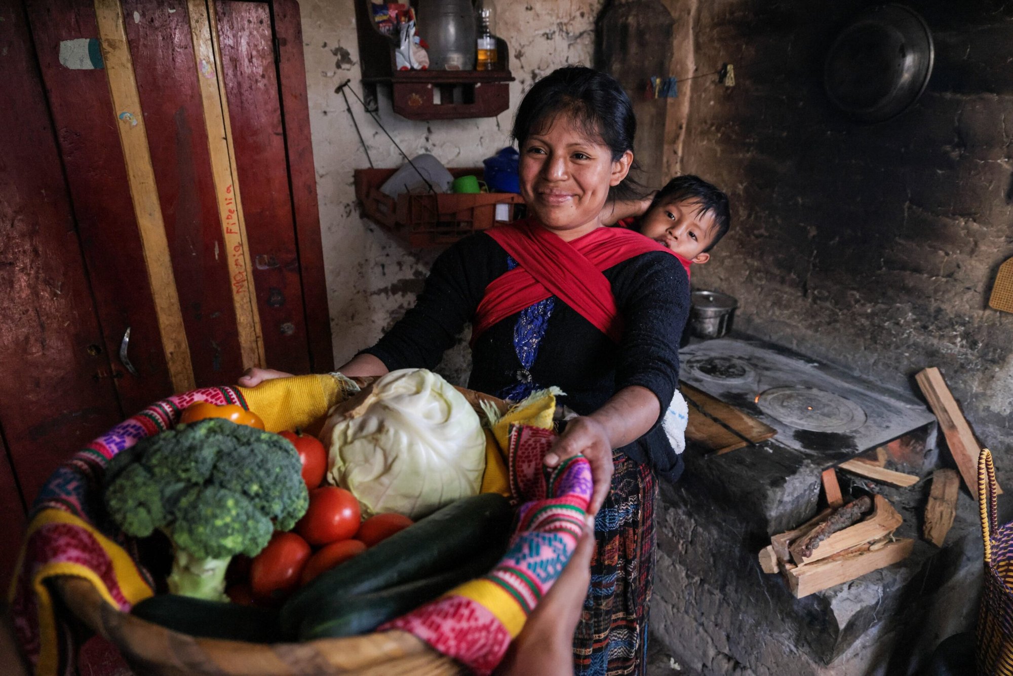 En una foto tomada en 2023, Ana Belén Mulul Yat, de 27 años, y su hijo, Joseph Gael Joj Mulul, de 1, reciben verduras de un productor en Pacacja Centro, Santa María Chiquimula, Guatemala. (Foto OSV News/Oscar Leiva, Silverlight para Catholic Relief Services)