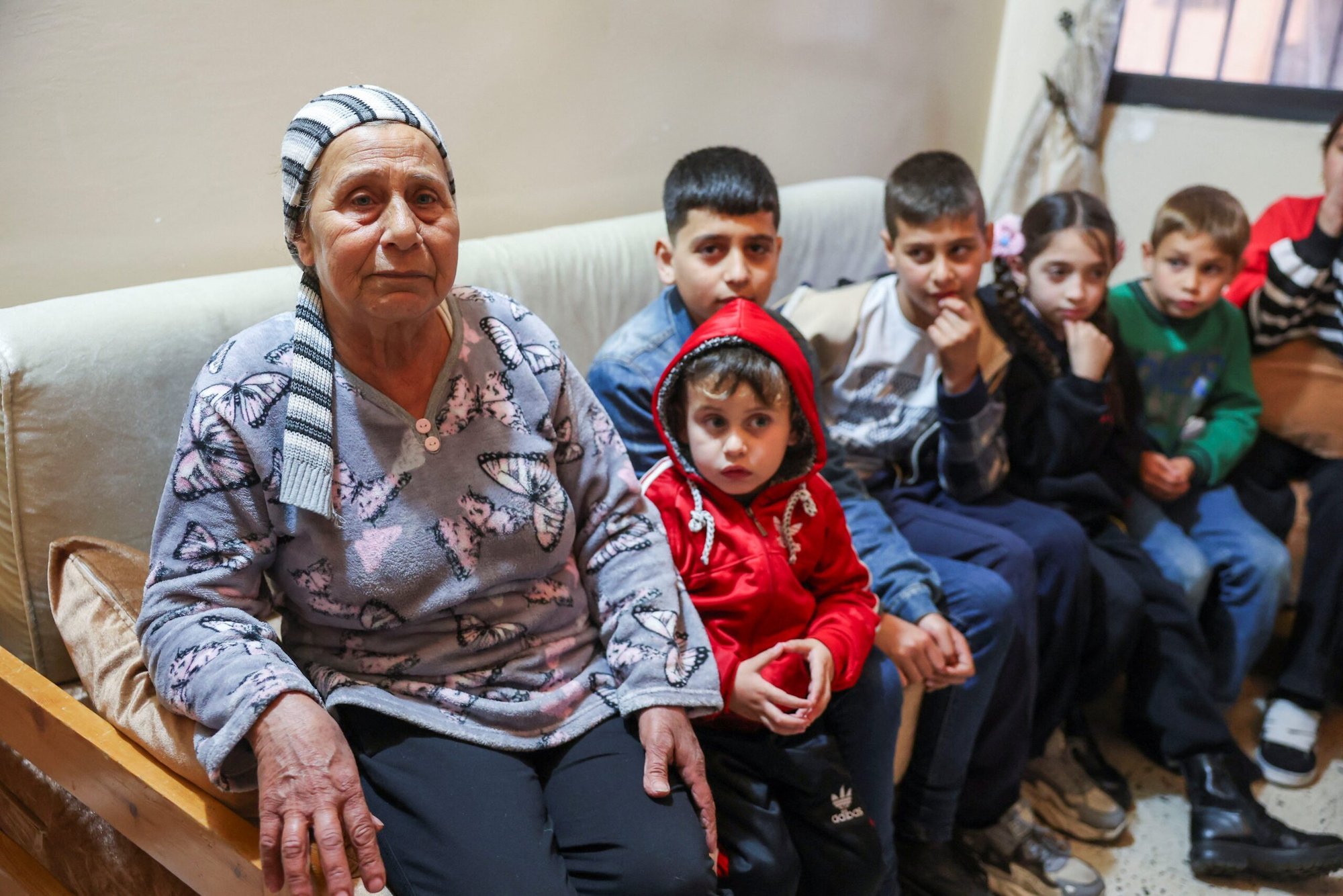 Nada Mohammed, que cruzó al Líbano el 9 de marzo de 2025 huyendo de la violencia en Siria occidental tras los asesinatos masivos de miembros de la minoría alauita en Siria occidental, se sienta con sus nietos en el barrio de Jabal Mohsen de Trípoli, Líbano, el 11 de marzo de 2025. (OSV News/Mohamed Azakir, Reuters)