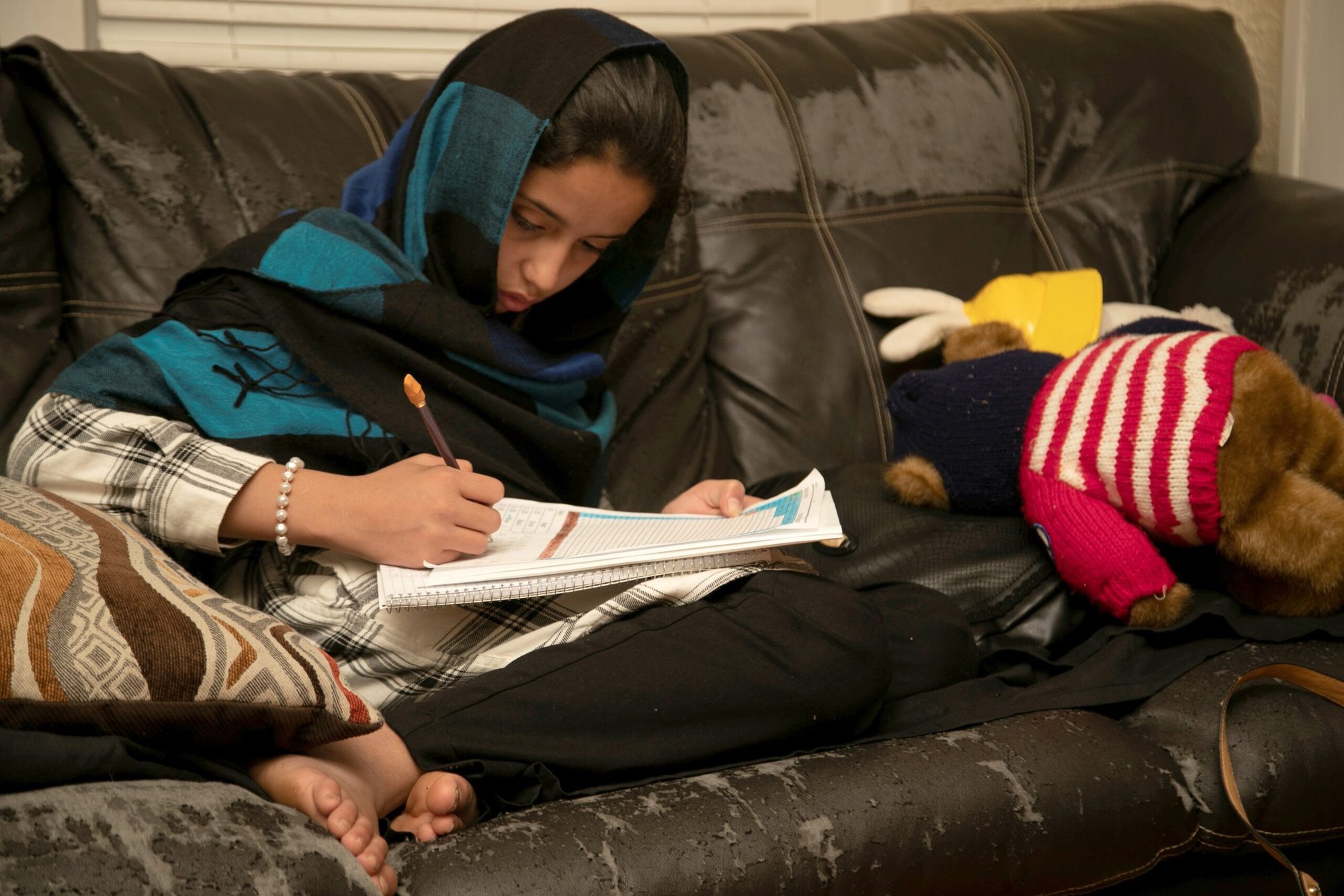 Una joven trabaja en sus tareas en su casa en Bowling Green, Kentucky, el 27 de noviembre de 2021. La familia Zadran, refugiados afganos que huyen de los talibanes, llegó a Bowling Green tras pasar una temporada en una base militar de Nuevo México. La Conferencia de Obispos Católicos de Estados Unidos dijo que no renovará sus acuerdos de cooperación con el gobierno federal relacionados con los servicios para niños y el apoyo a los refugiados después de que sus asociaciones de larga data con el gobierno federal en esas áreas se volvieran “insostenibles”. (Foto OSV News/Amira Karaoud, Reuters)