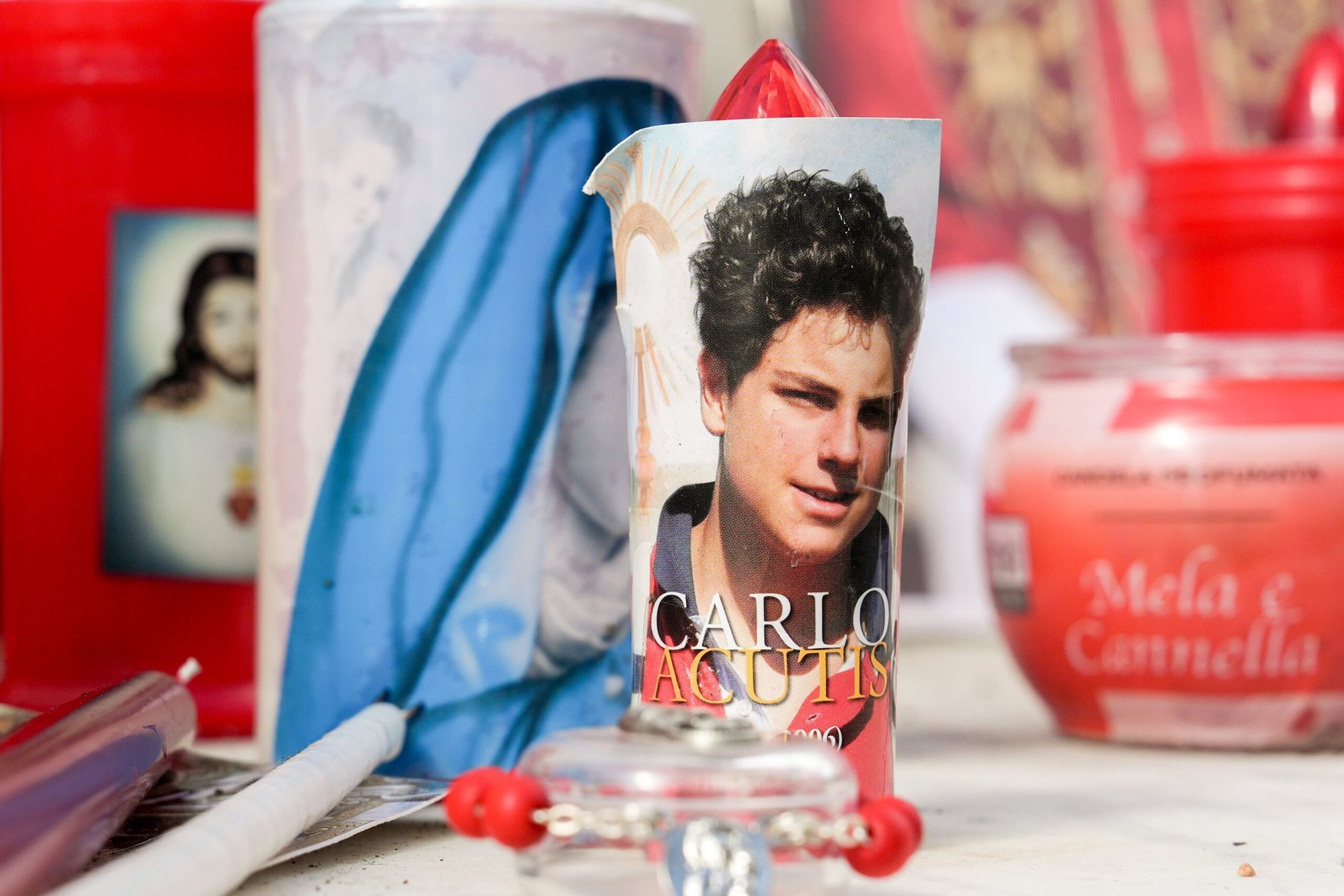 Velas votivas e imágenes religiosas, incluyendo una del Beato Carlo Acutis, se ven en la base de una estatua de San Juan Pablo II fuera del hospital Gemelli de Roma el 27 de febrero de 2025, mientras el Papa Francisco estaba siendo tratado allí por una neumonía doble. (CNS photo/Lola Gomez)