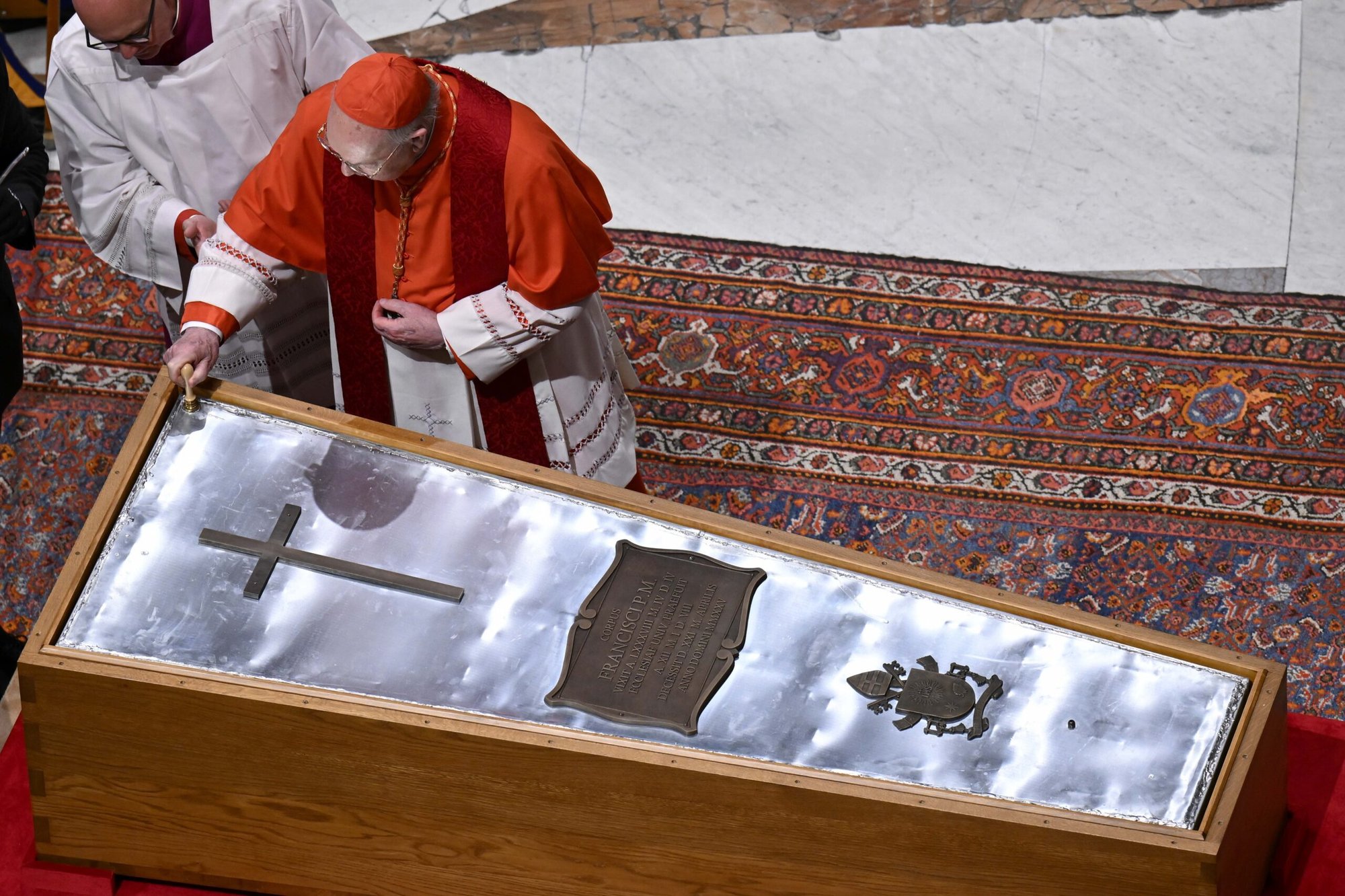 El cardenal estadounidense Kevin J. Farrell, camarlengo de la Santa Iglesia Romana, coloca un sello en la cubierta de zinc del ataúd del Papa Francisco mientras es sellado durante un servicio de oración en la Basílica de San Pedro en el Vaticano el 25 de abril de 2025. (Foto CNS/Vatican Media)