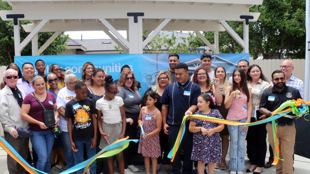 Las familias beneficiarias de nuevas casas de Habitat for Humanity cortan la cinta durante un acto de bendición el 12 de julio, con la participación del obispo auxiliar de Los Ángeles, Matthew Elshoff. (Giacomo Ammazzalorso)
