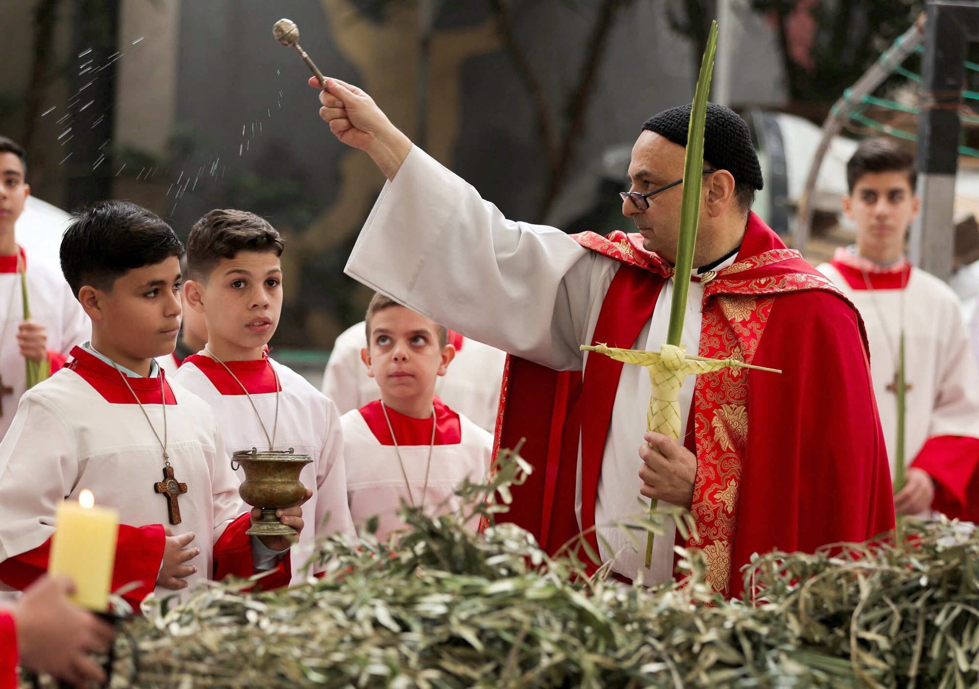 El padre Gabriel Romanelli, párroco de la Parroquia de la Sagrada Familia de la ciudad de Gaza, bendice a la congregación con agua bendita durante una Misa del Domingo de Ramos en la iglesia, el 29 de marzo de 2026. (Foto OSV News/Dawoud Abu Alkas, Reuters)