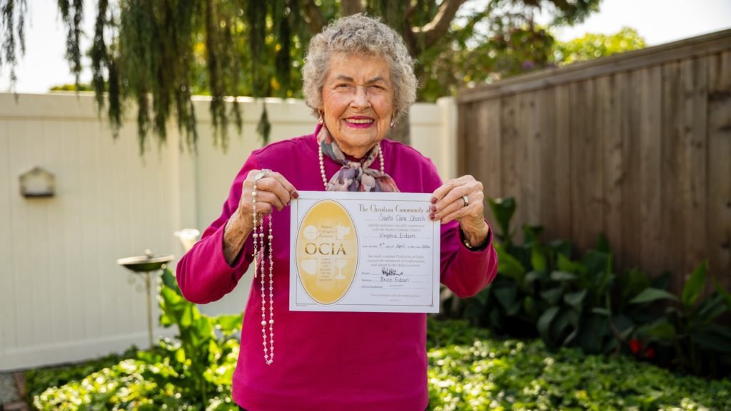 Una mujer de 98 años, Virginia Eidson, sostiene su certificado de OCIA (Orden de Iniciación Cristiana de Adultos), que documenta su ingreso a la Iglesia Católica. (Reese Cuevas)