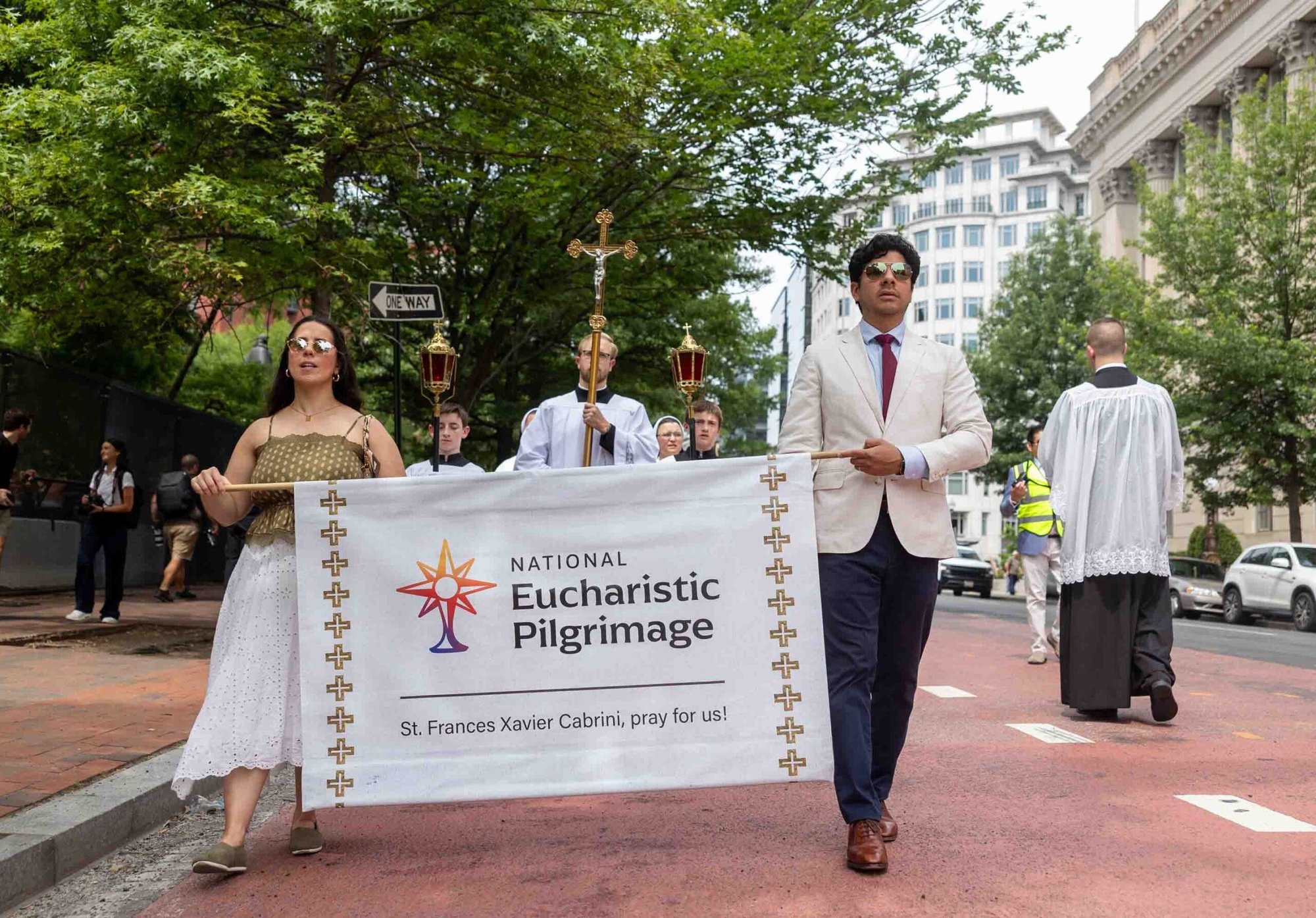 Un hombre y una mujer sostienen una pancarta de la Peregrinación Eucarística Nacional 2026 mientras encabezan una procesión eucarística por las calles de Washington el 6 de junio. (Foto OSV News/Mihoko Owada, Catholic Standard)