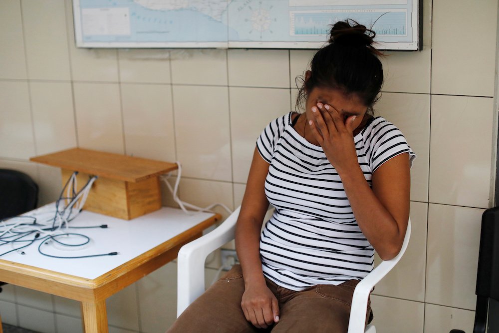 A Honduran woman holds back tears while waiting in a migrant shelter in Guatemala City