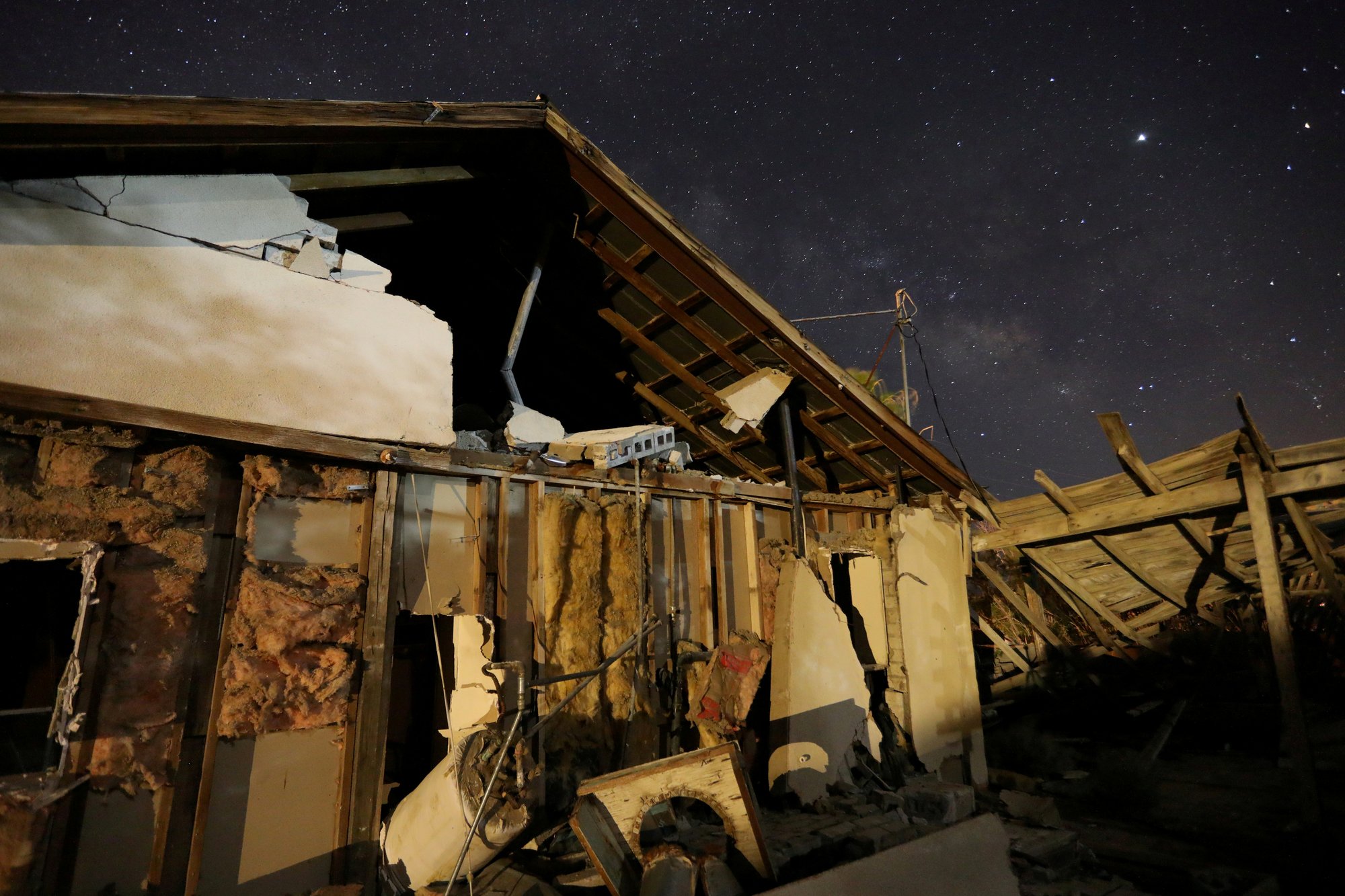 A house destroyed by a powerful 7.1 magnitude earthquake is seen at night near Trona