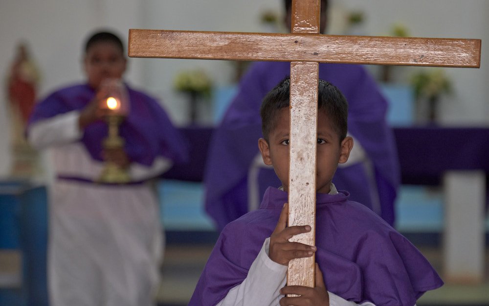 A boy carries the cross out of the sanctuary at the end of Catholic Mass in Lethem
