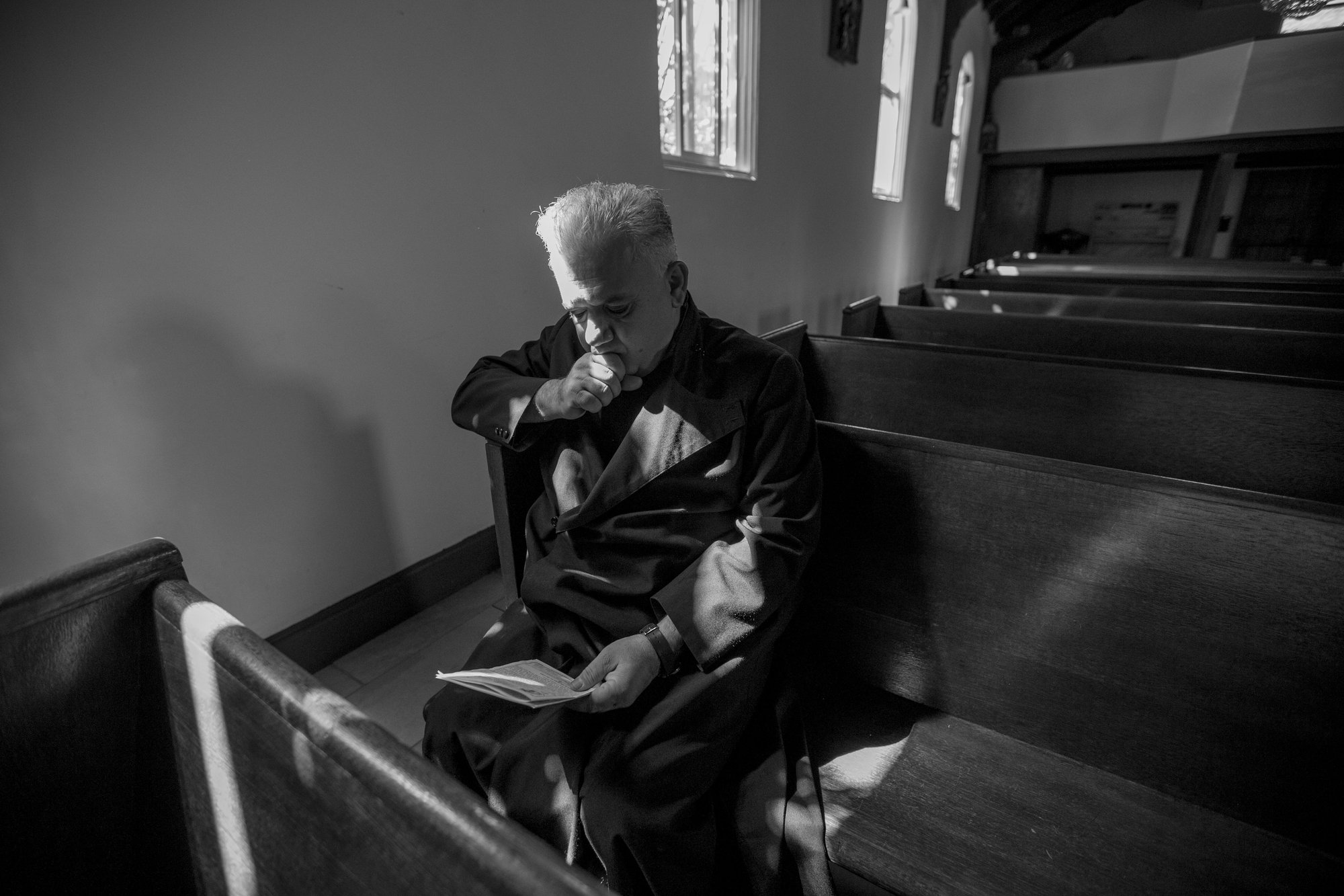 Fr. Bedrossian sitting in the pews that he refurbished for Our Lady Queen of Martyrs Church.