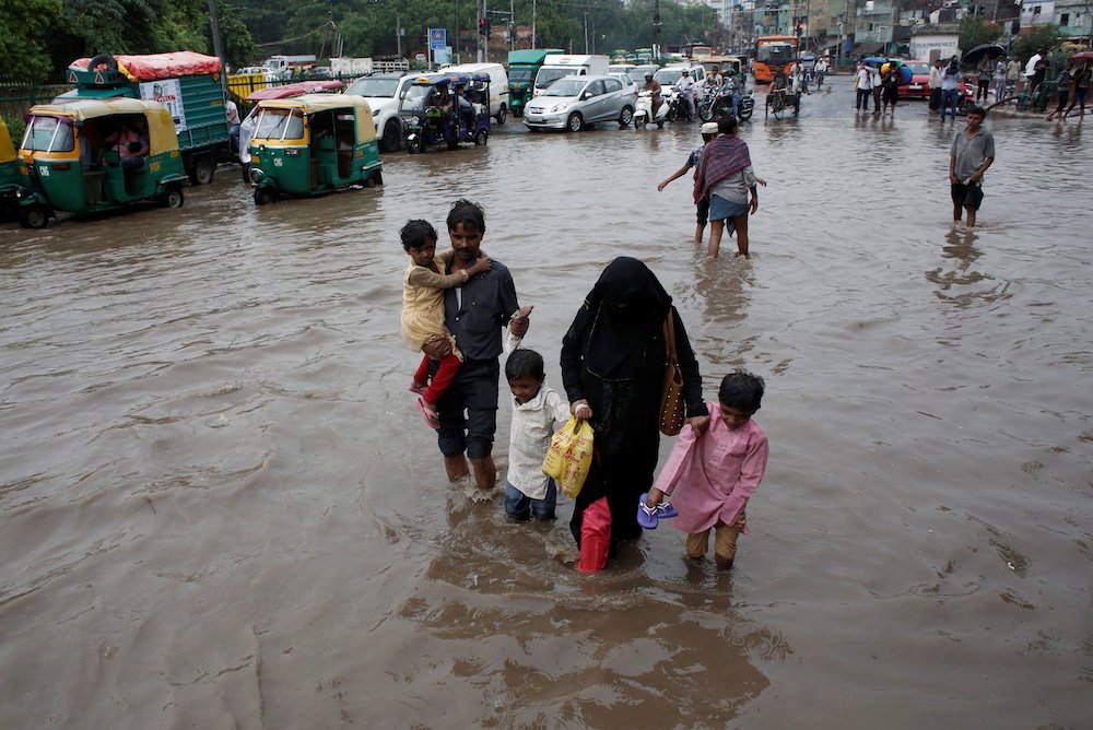 A family wades through a flooded street during heavy rains in New Delhi