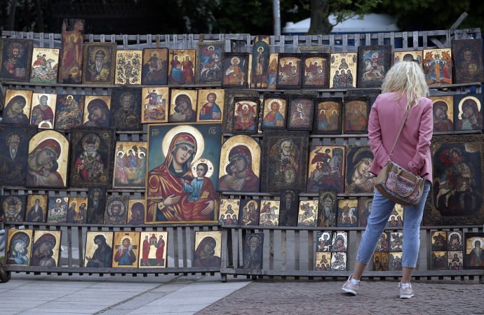 A woman looks at Orthodox icons in an open air market near the Alexander Newsky cathedral
