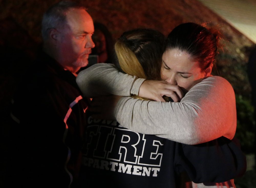 A woman who fled the Borderline Bar and Grill is embraced by a first responder Nov. 8 after a gunman killed at least 13 people. The gunman