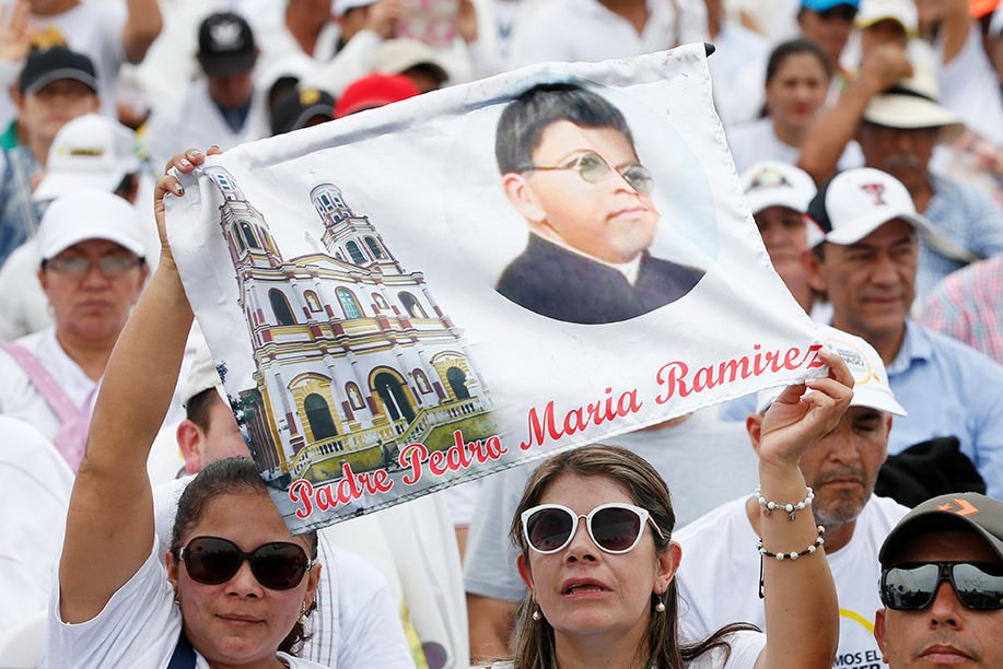 A woman holds a picture of Father Pedro Maria Ramirez during Mass at Catama field in Villavicencio