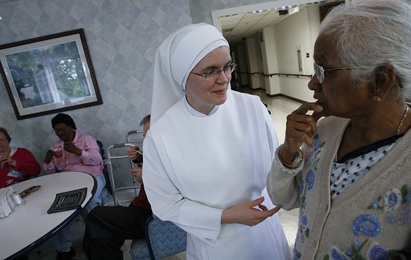 A member of the Little Sisters of the Poor assists a woman at the Little Sisters’ Jeanne Jugan Residence in Washington in this 2009 photo. (CNS file photo)