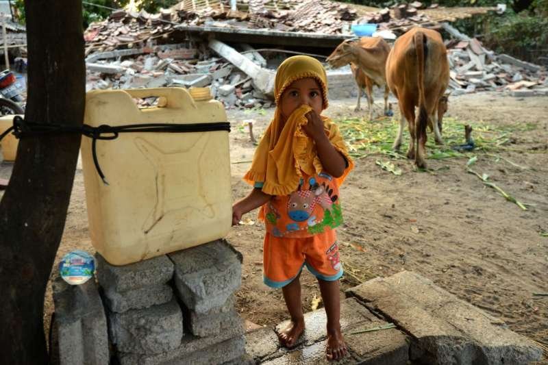 A child stands in front of debris after an Aug. 5 earthquake on Indonesia’s Lombok island. Credit: Sonny Tumbelaka / AFP / Getty.