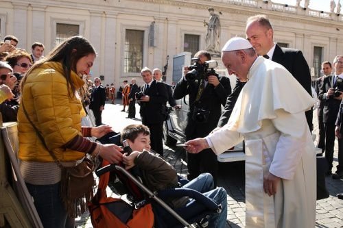 Pope Francis gives a rosary to a disabled child during his general audience Feb. 24