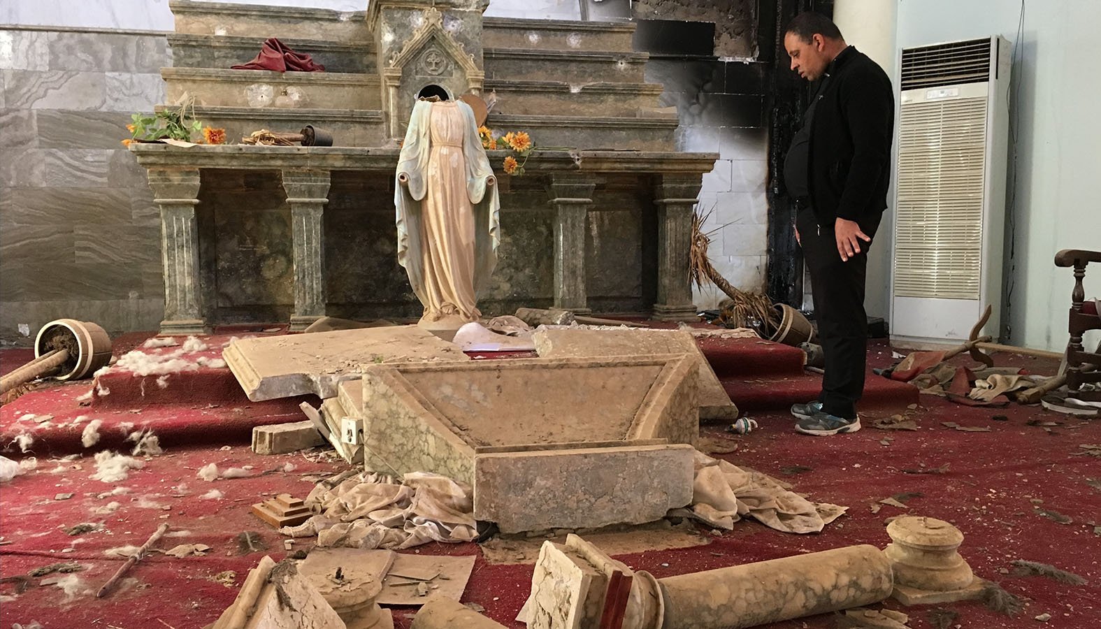 A Catholic church destroyed by Islamic State militants in Karamdes, Iraq, is examined by a priest March 6, 2018. The genocide conducted by the Islamic State against Christian communities in Iraq and Syria has turned into continued harassment by Iran-backed militias and shows no signs of abating soon, said speakers at a Sept. 26, 2019, hearing in Washington. (CNS photo/courtesy Archdiocese of Irbil)