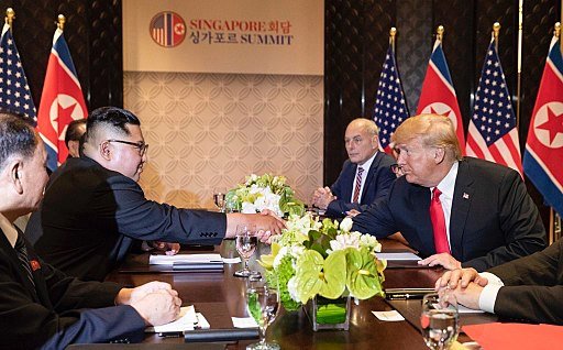 Kim Jong Un and President Trump shake hands across a table at the Singapore Summit. (Wikimedia Commons)
