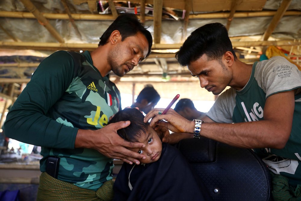 A Rohingya refugee boy has his hair cut at a refugee camp in Cox's Bazar