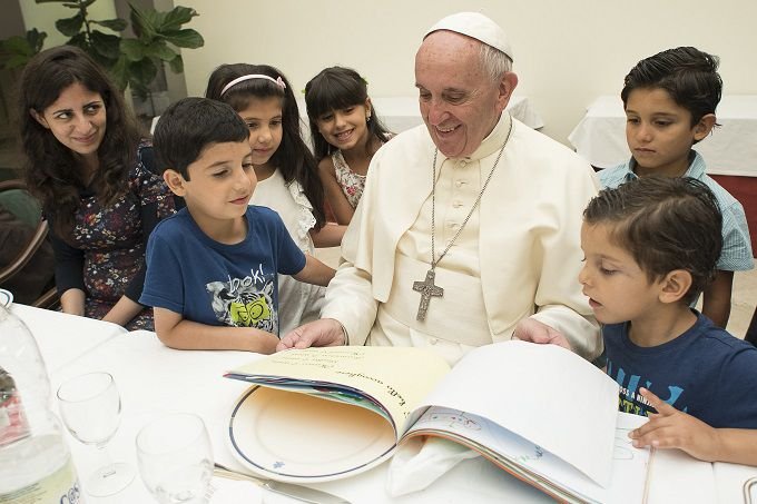 Pope Francis eats lunch with 21 Syrian refugees in the Casa Santa Marta Aug. 11