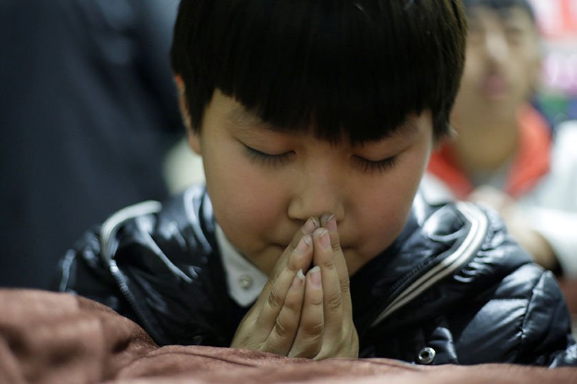 A boy prays during a Christmas Eve Mass at a Catholic church on the outskirts of Taiyuan